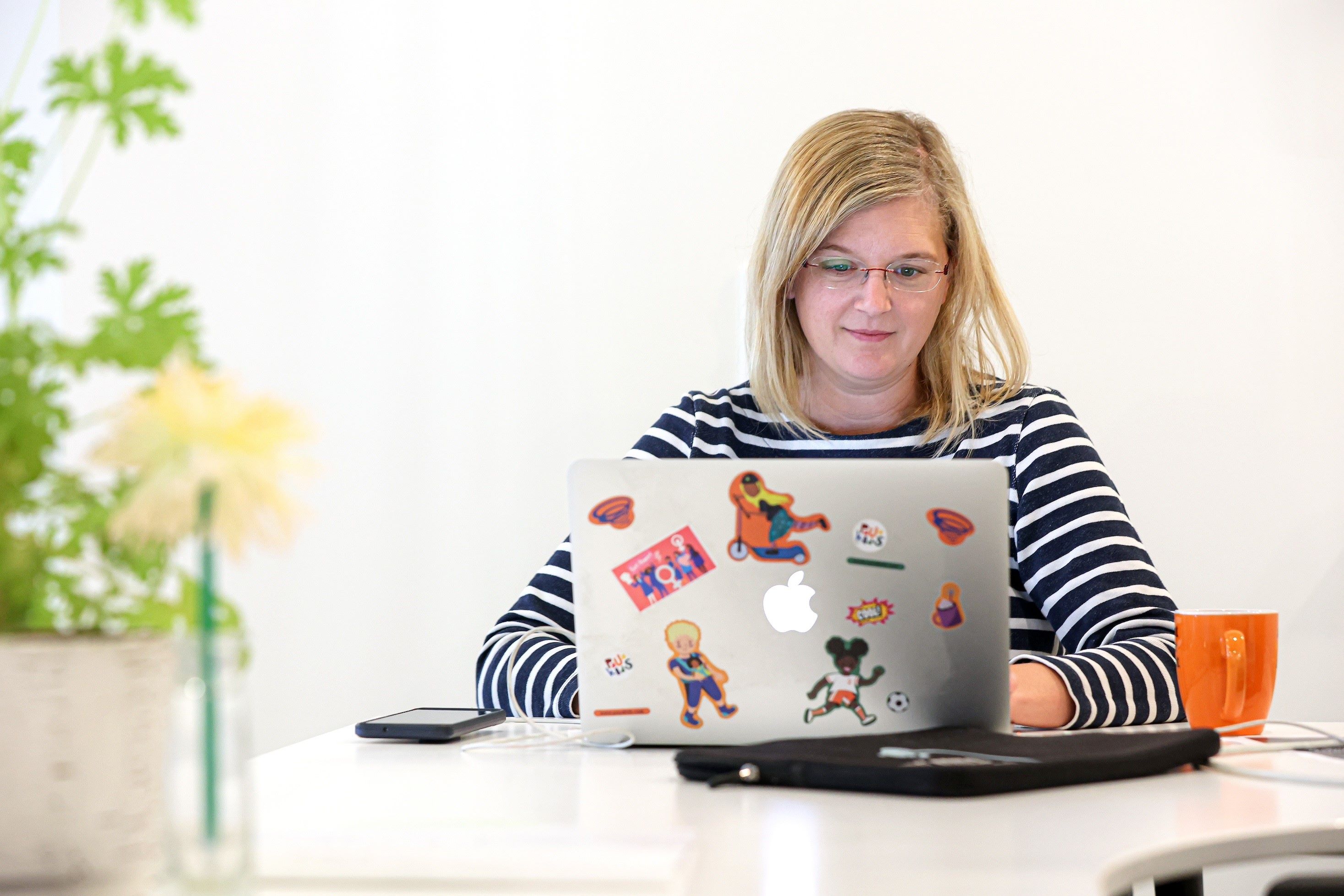 Cornelia Aigenberger sitzt vor ihrem Macbook an einem Schreibtisch