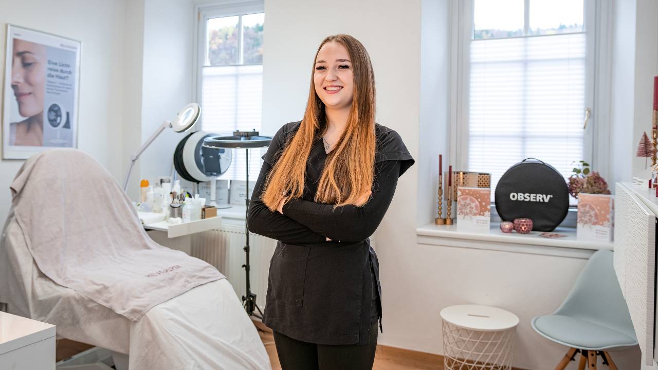Kosmetikerin blickt lächelnd in die Kamera
