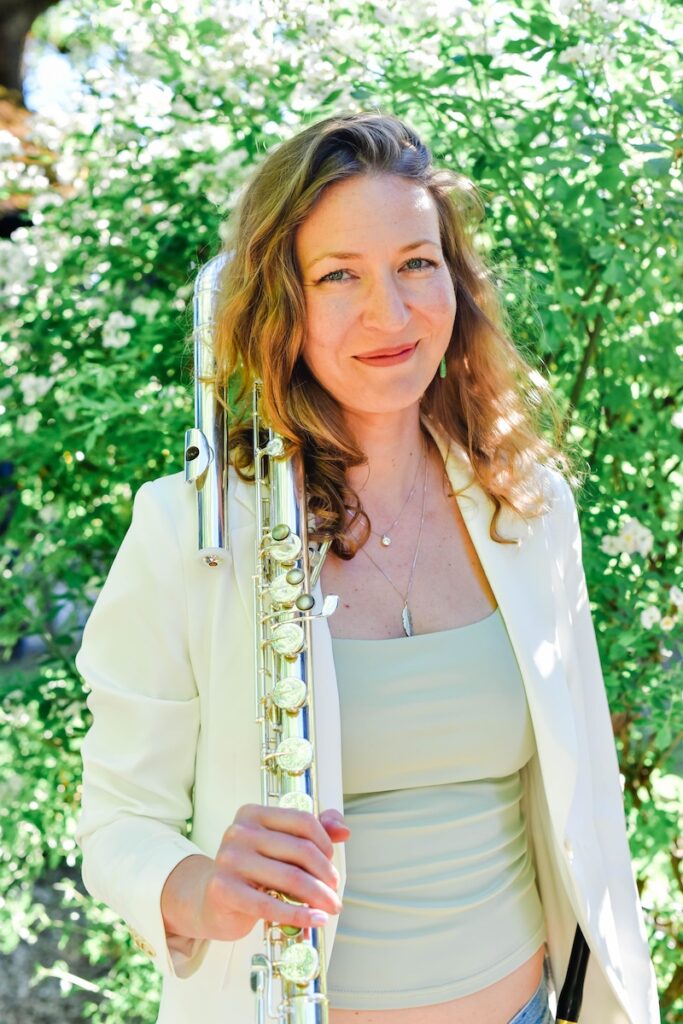 Portr&auml;tfoto: Person h&auml;lt Querfl&ouml;te im Freien vor gr&uuml;nem Hintergrund