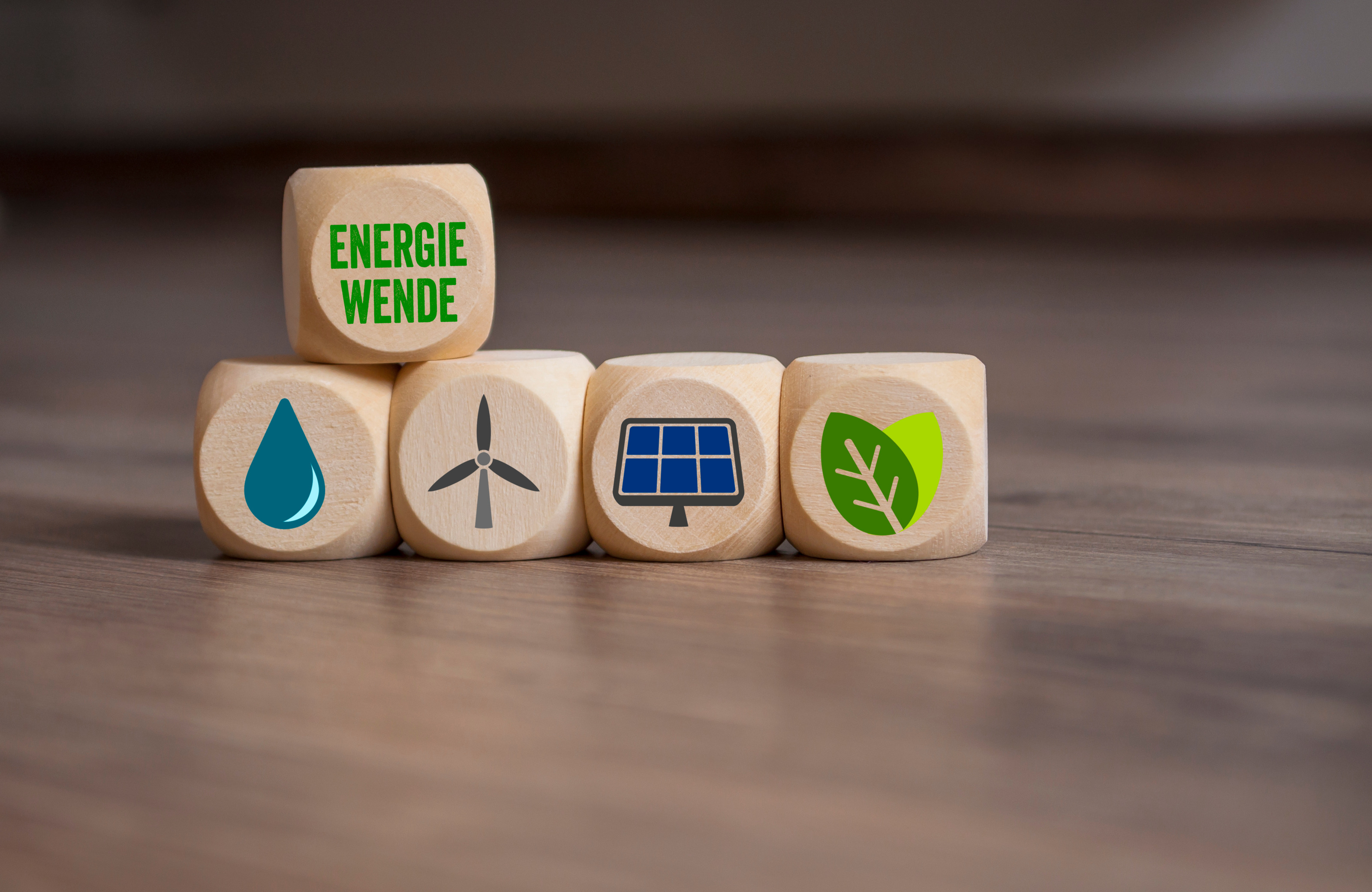 Mehrere Holzwürfel nebeneinander positioniert mit Symbolen zum Thema Nachhaltigkeit, oben auf ein weitere Holzwürfel mit dem Schriftzug Energiewende