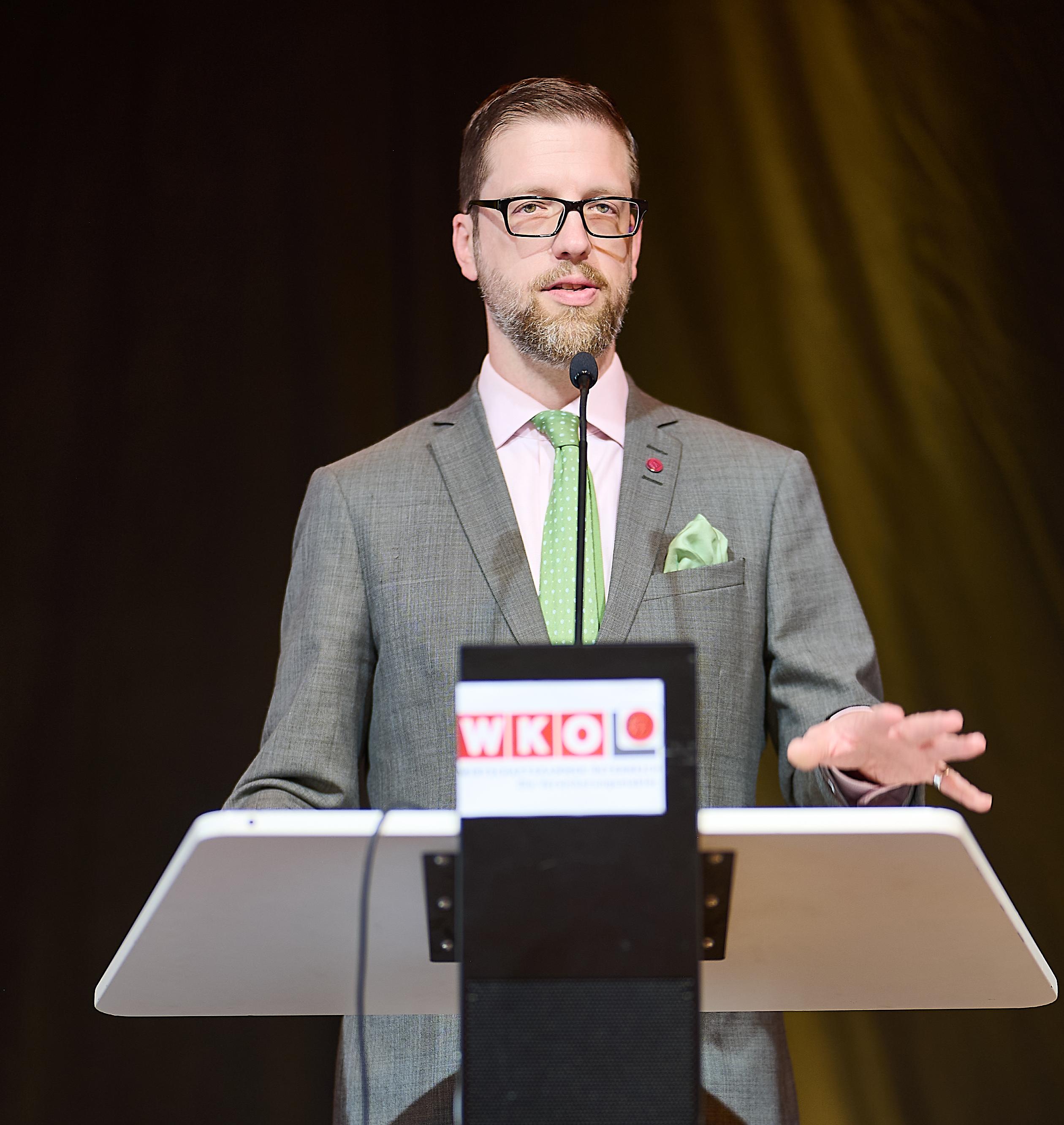 Person vor einem Podium h&auml;lt Vortrag