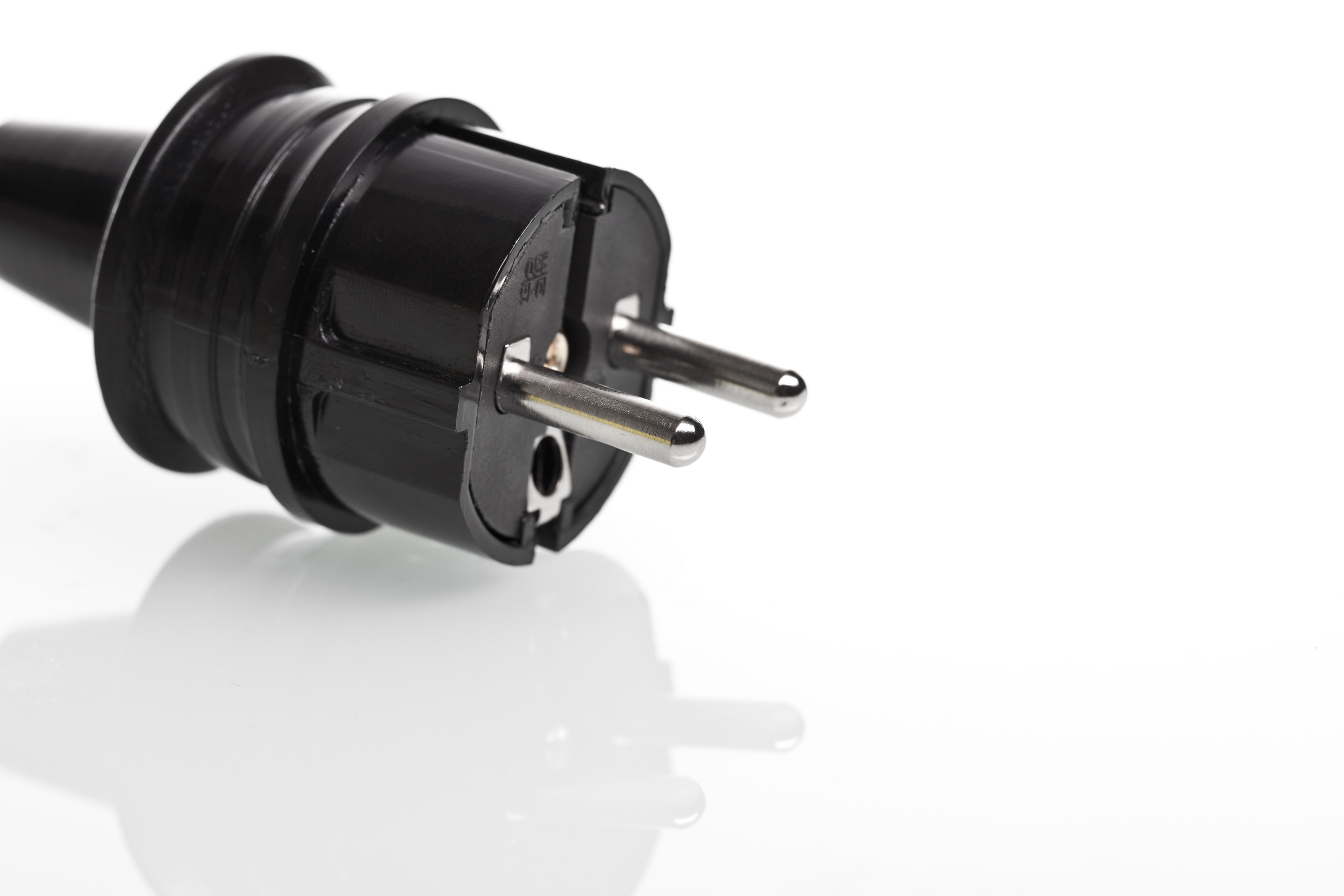 Detailansicht eines schwarzen Stromsteckers auf weißem Hintergrund