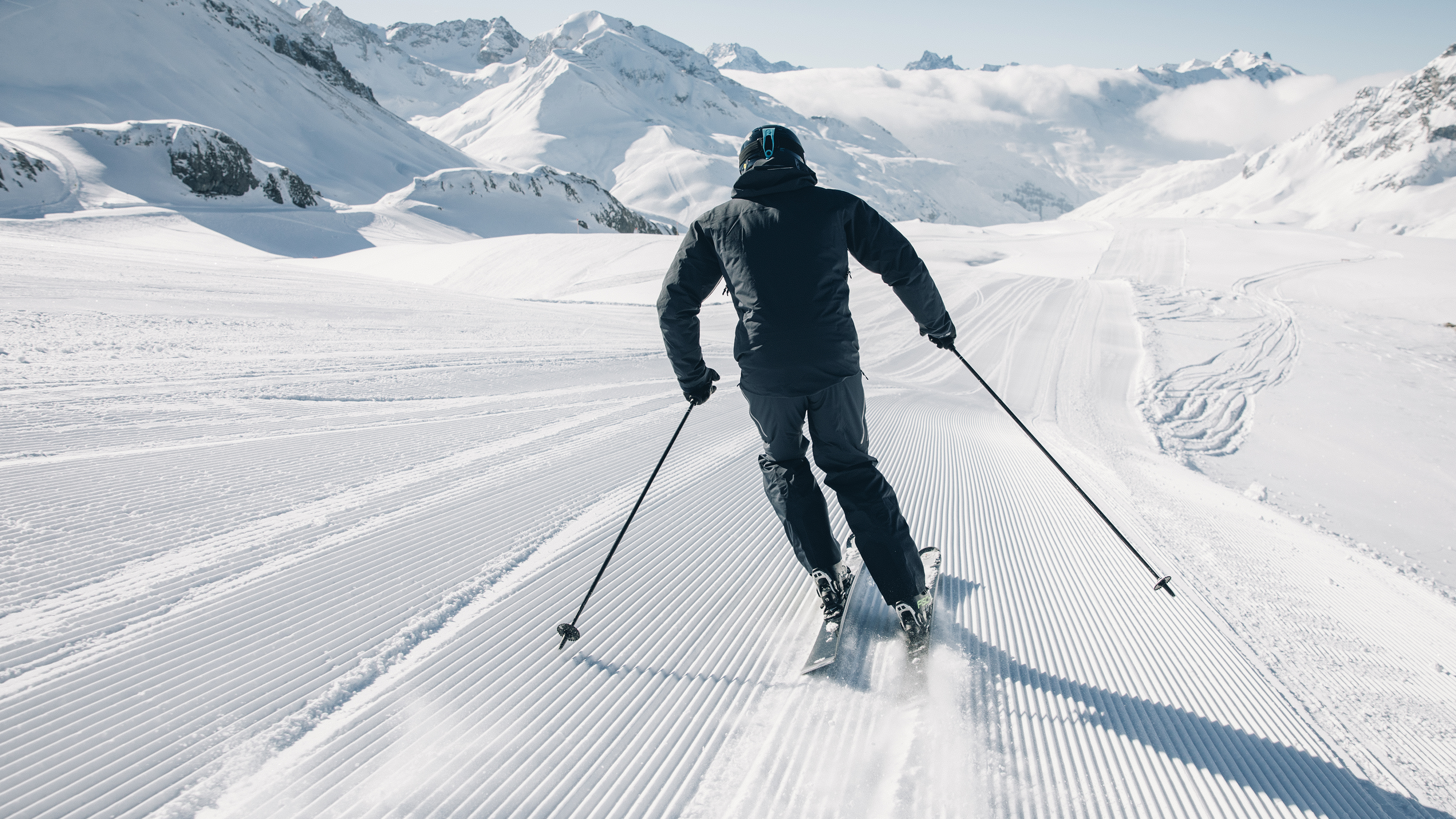 Skifahrende Person von Hinten, Schneepiste und vescheite Berge