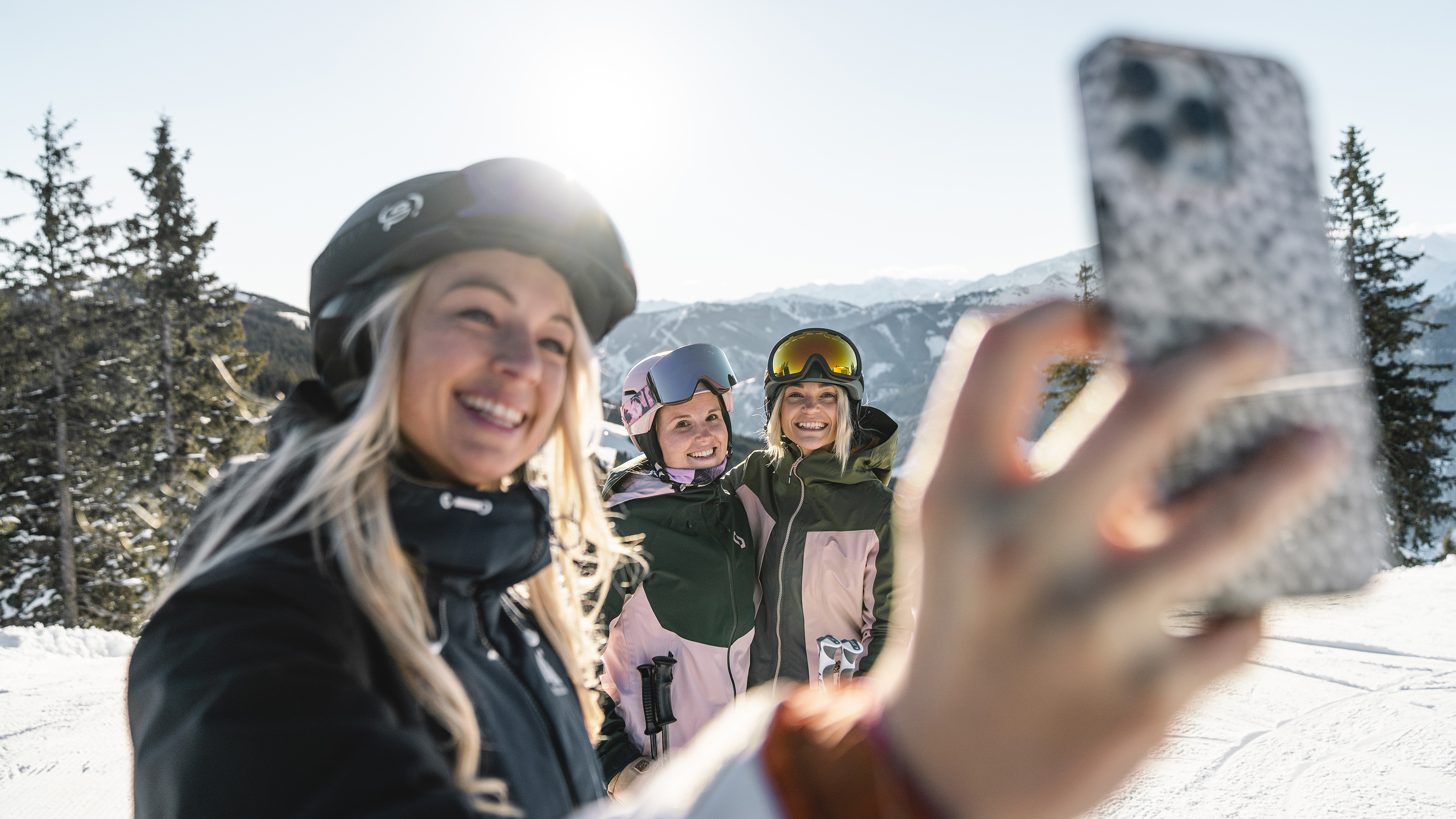 Drei Personen in einer Winterlandschaft. Person im Vordergrund macht ein Selfie.