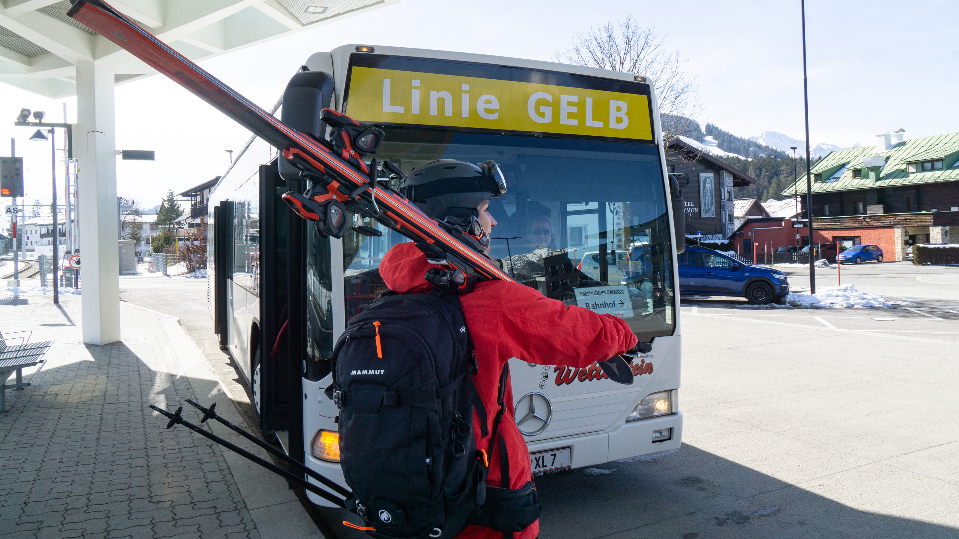 Person mit Skiausrüstung vor einem Autobus 