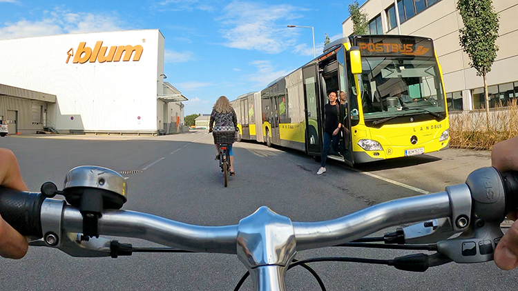 Detailansicht Fahrradlenkstange mit Blick auf Personen aus Bus steigend und radfahrender Person