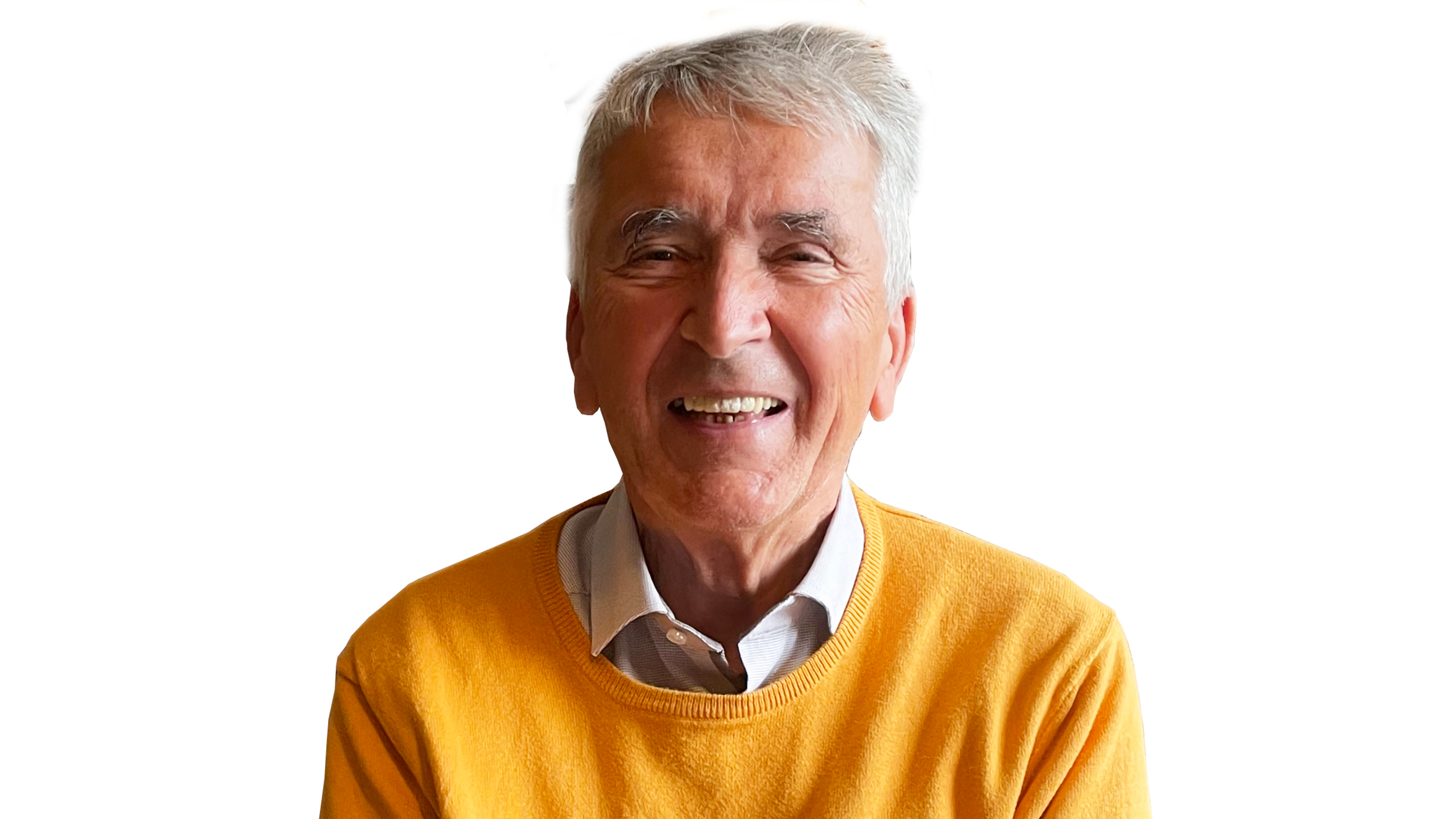 Portrait einer lächelnden Person in gelbem Pullover vor weißem Hintergrund