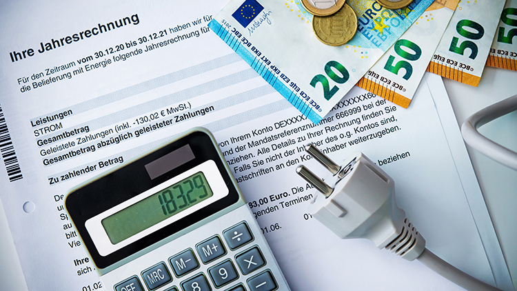 Taschenrechner, Stromstecker und Eurovaluten auf Dokument mit Schriftzug Jahresabrechnung liegend