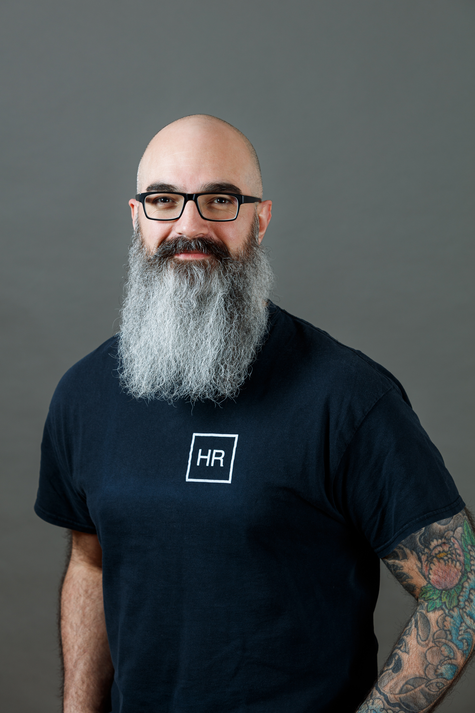 Portr&auml;tfoto: Person mit Glatze, Brille und langem grauem Bart, schwarzes T-Shirt mit Aufdruck &bdquo;HR&ldquo;