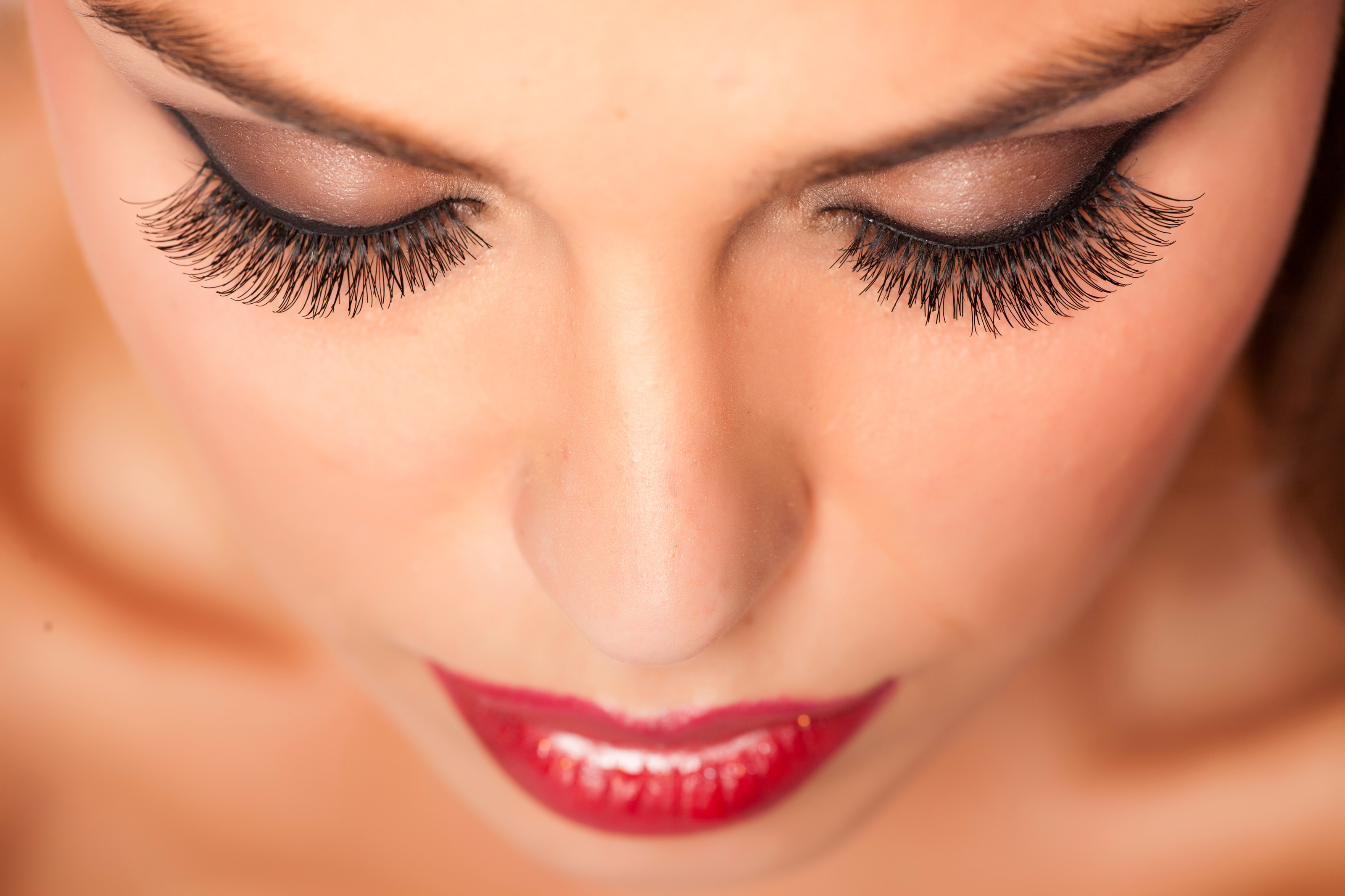 Nahaufnahme des Gesichts einer Person mit geschlossenen Augen. Die Person hat auf den Lidern Lidschatten, Make-up im Gesicht und tr&auml;gt Lippenstift