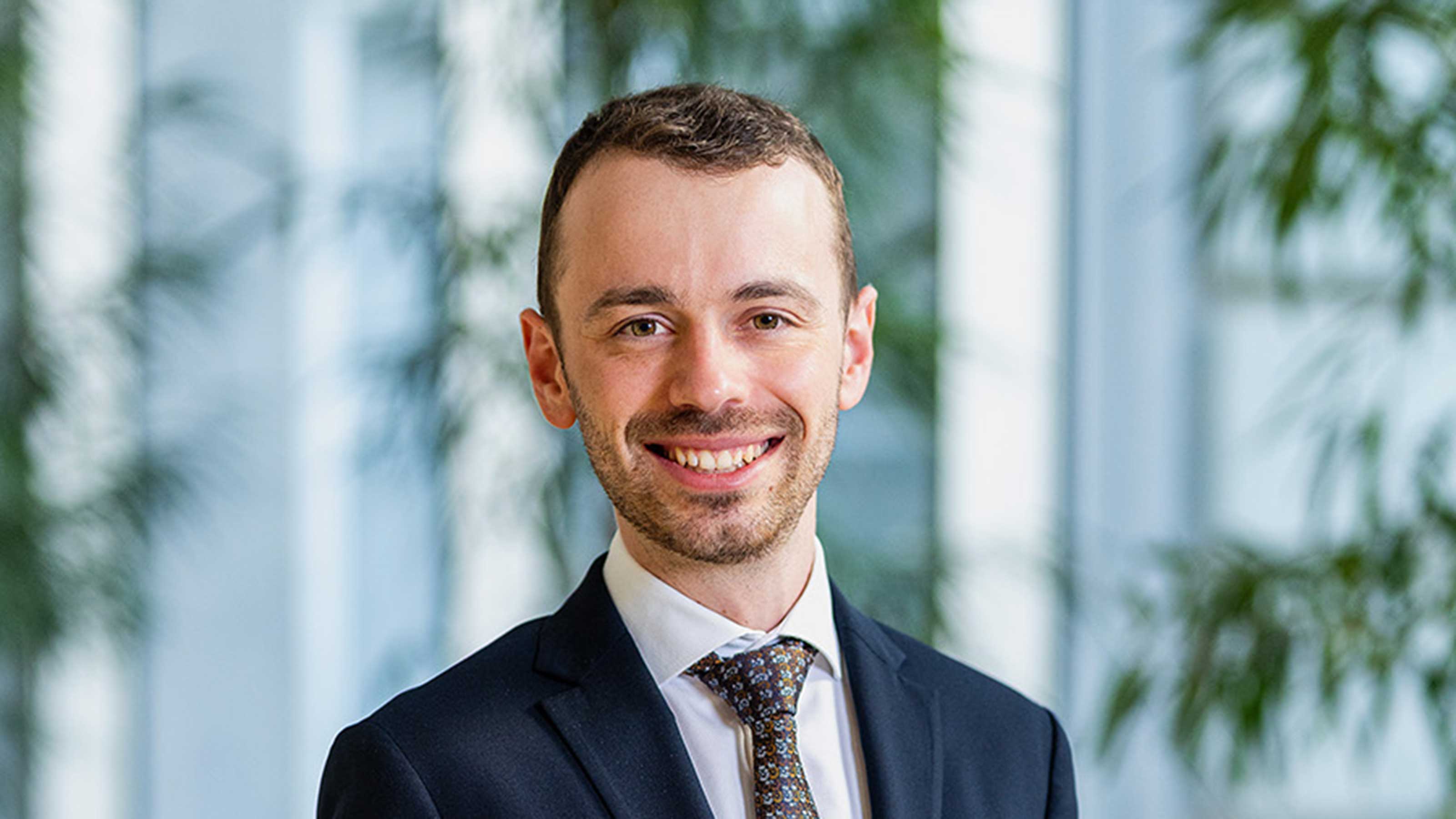 Person im dunklen Anzug mit Krawatte in einem B&uuml;rogeb&auml;ude
