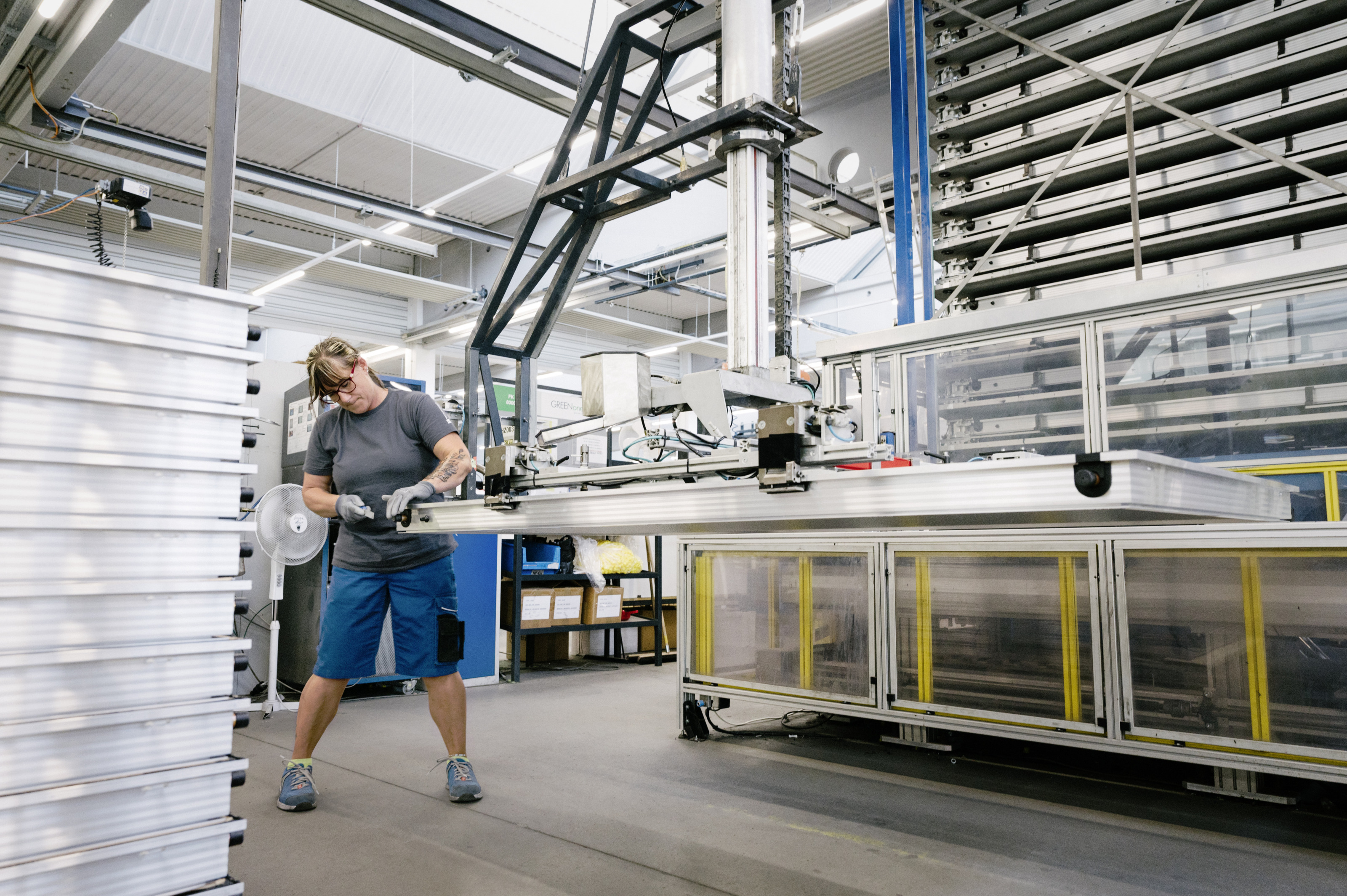 Person steht in Industriest&auml;tte und bearbeitet Solarpaneel