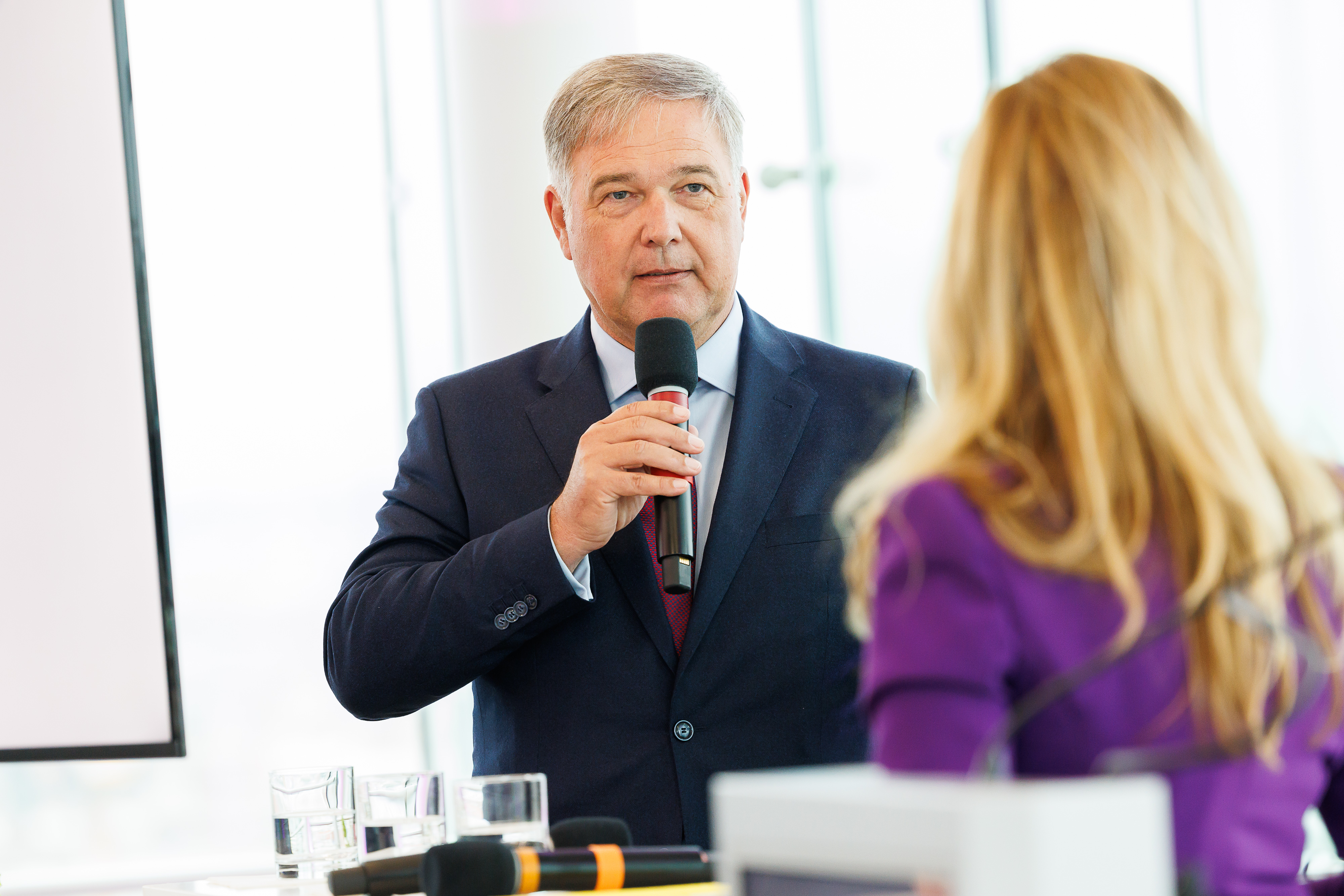 Person im Anzug spricht zu einer Dame vor dem Publikum