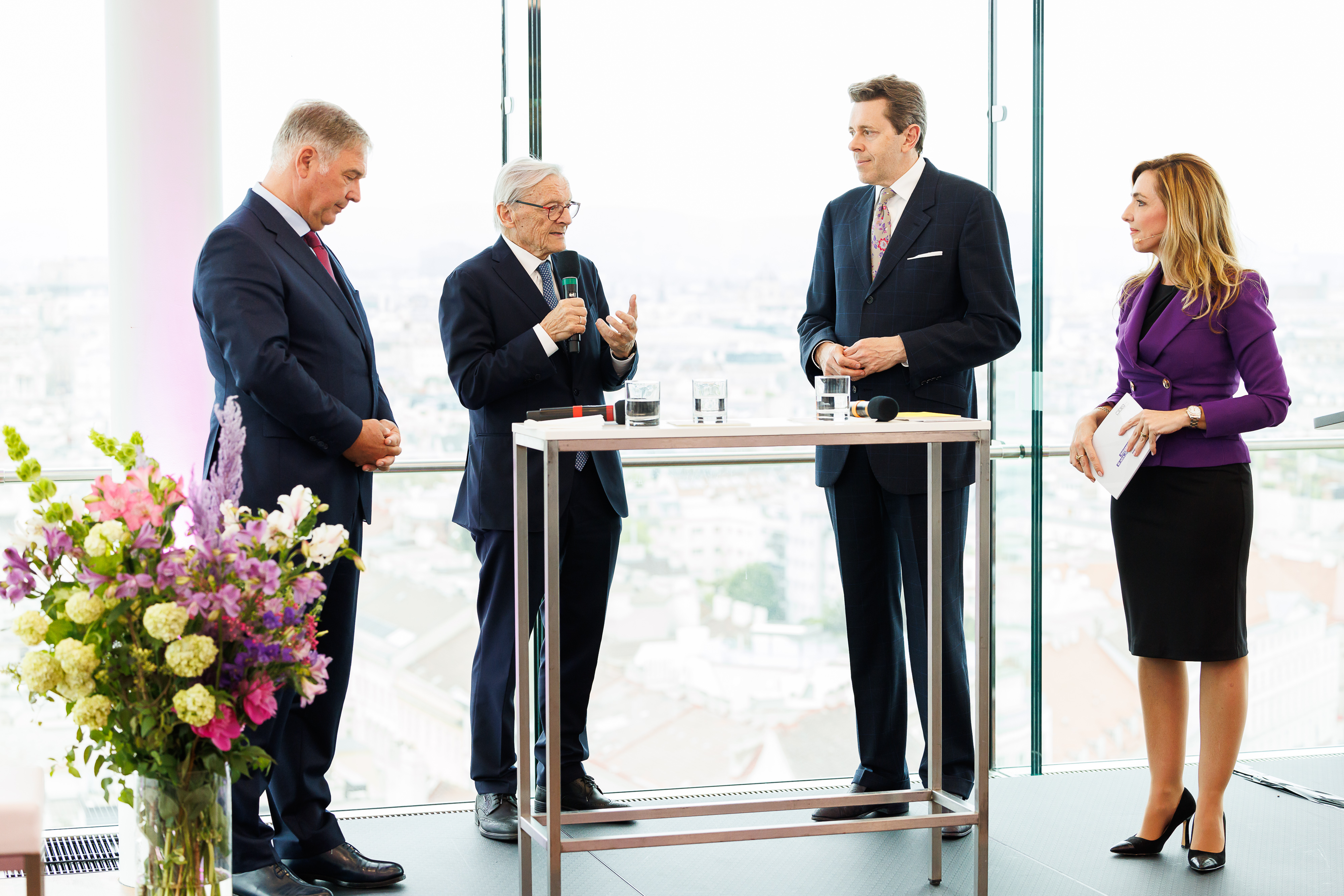 Schick gekleidete Personen sprechen vor dem Publikum