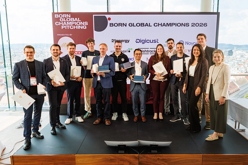Personengruppe mit Urkunden auf einer B&uuml;hne vor der Veranstaltungswand &bdquo;Born Global Champions 2026&ldquo;.