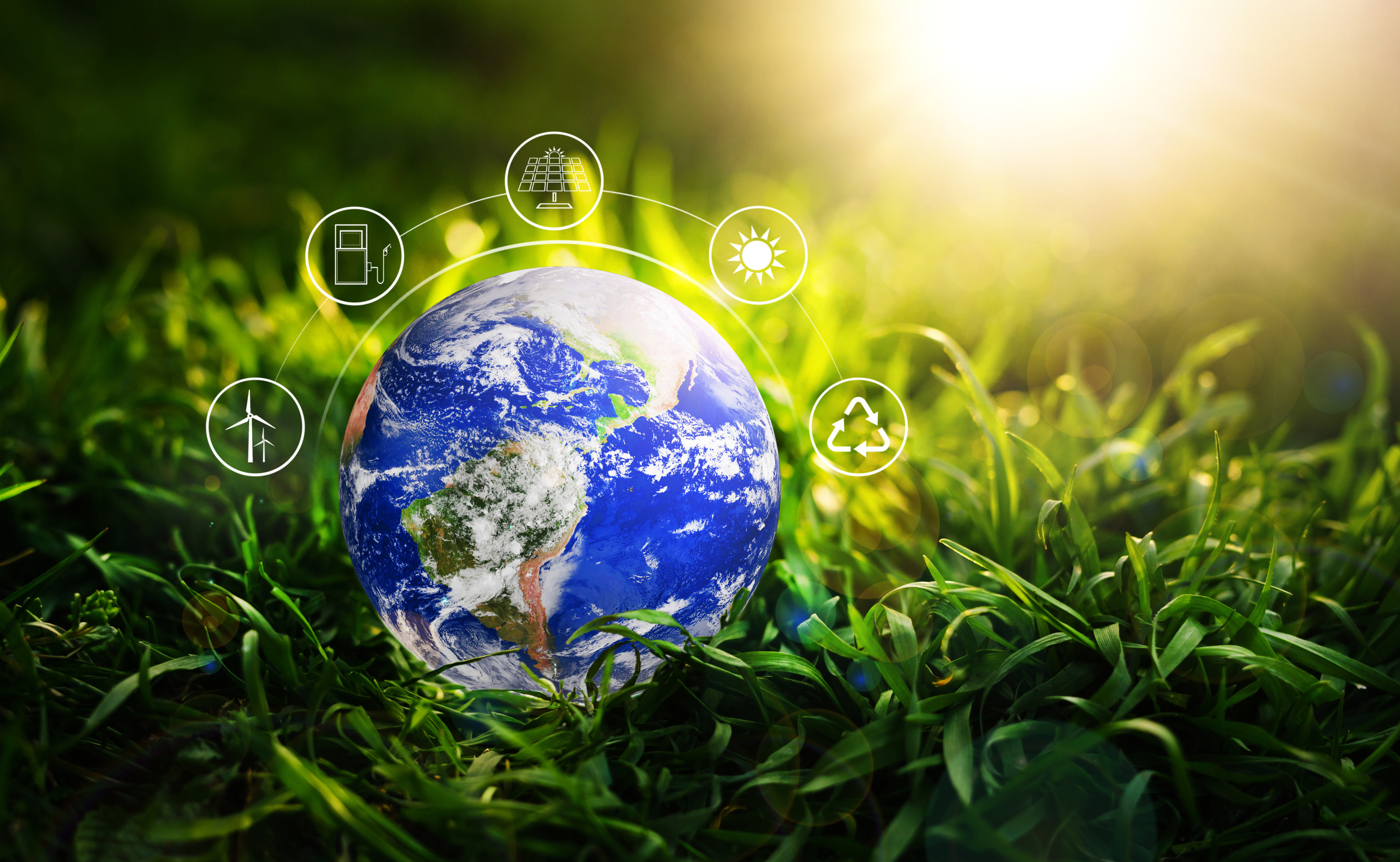 Weltkugel ist auf einem gr&uuml;nen Gras platziert, dar&uuml;ber zeigt sich eine grafische Visualisierung zum Thema Umwelt, Energie und Nachhaltigkeit, Sonnenstrahlen ragen von oben in das Bild hinein