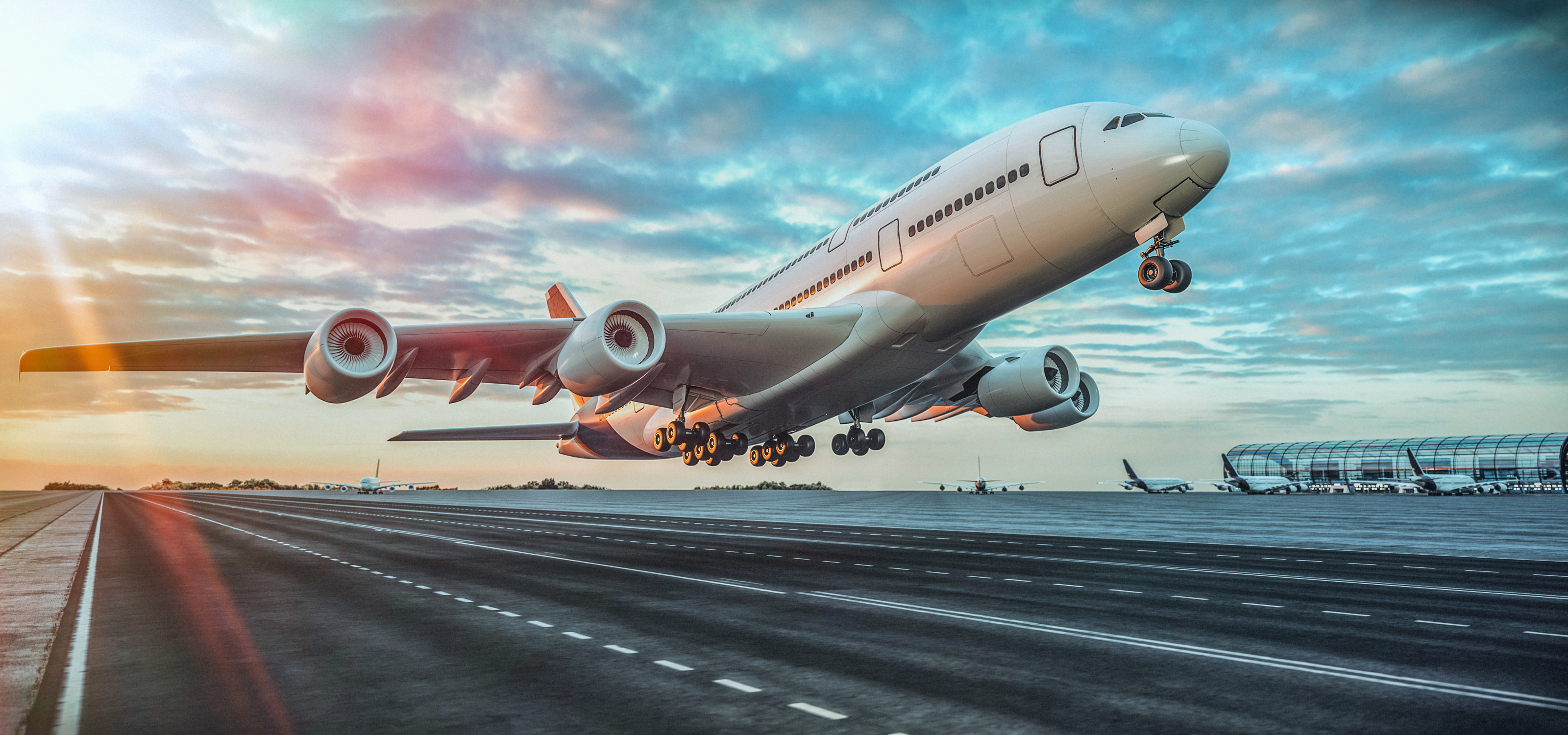 Gro&szlig;es Flugzeug beim Starten auf Landebahn im Licht des Sonnenuntergangs, im Hintergrund weitere Flugzeuge parkend