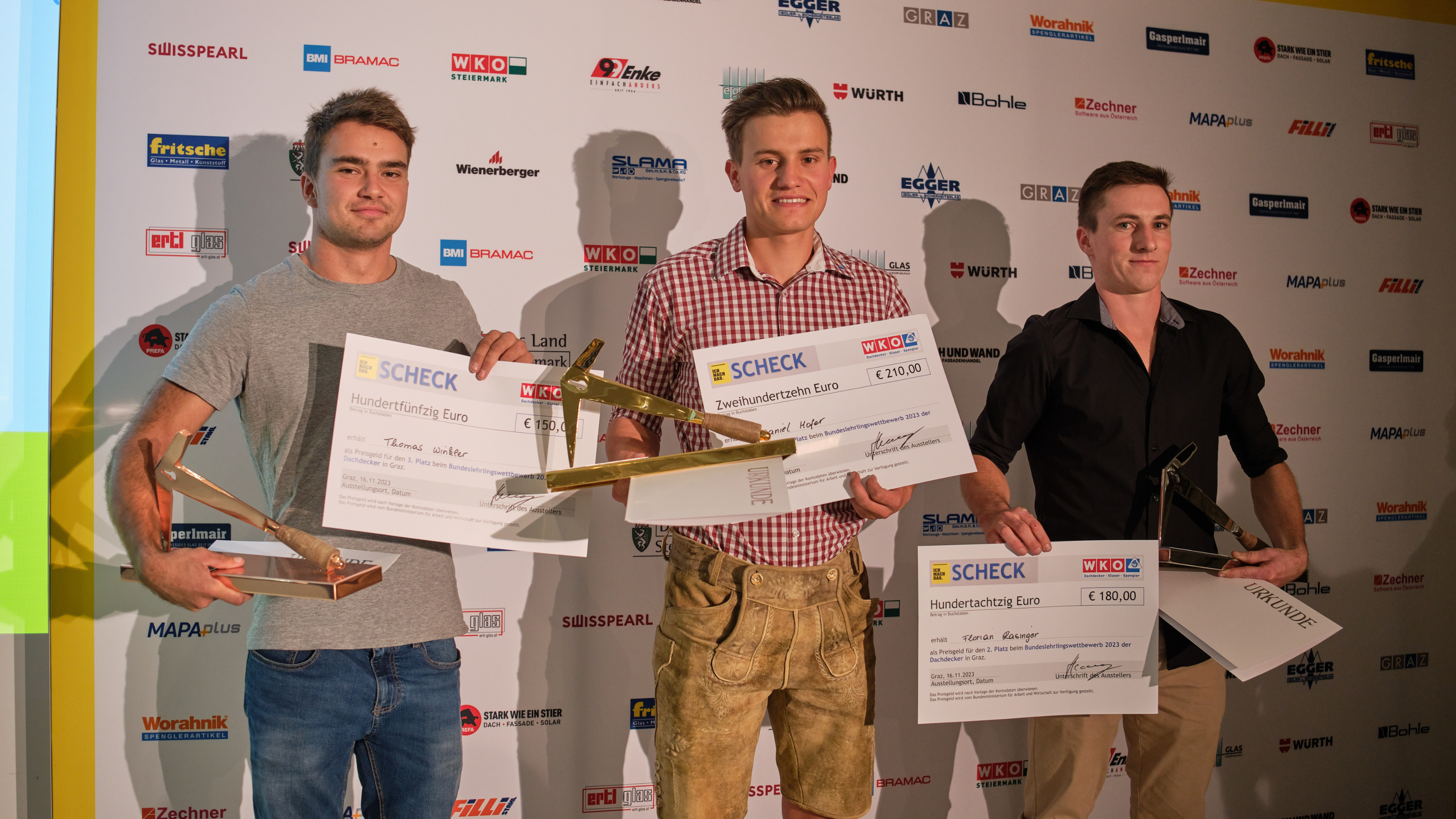 3 junge Männer posieren mit Pokalen und Schecks
