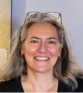 Portraitfoto einer l&auml;chelnden Person mit Brille auf dem Kopf vor hellem Hintergrund