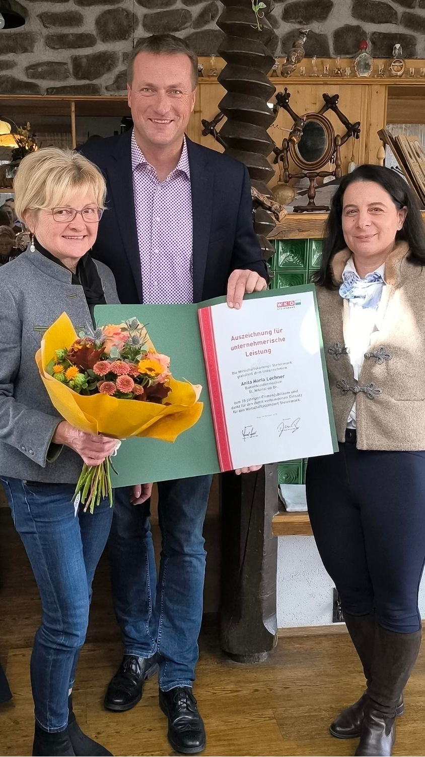 2 Frauen und 1 Mann halten Urkunde und Blumenstrauß