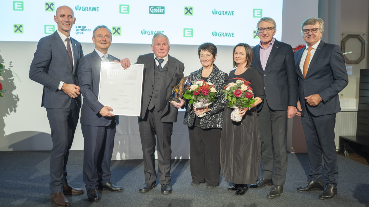 Frauen und Männer auf einer Bühne mit einer Urkunde in der Hand