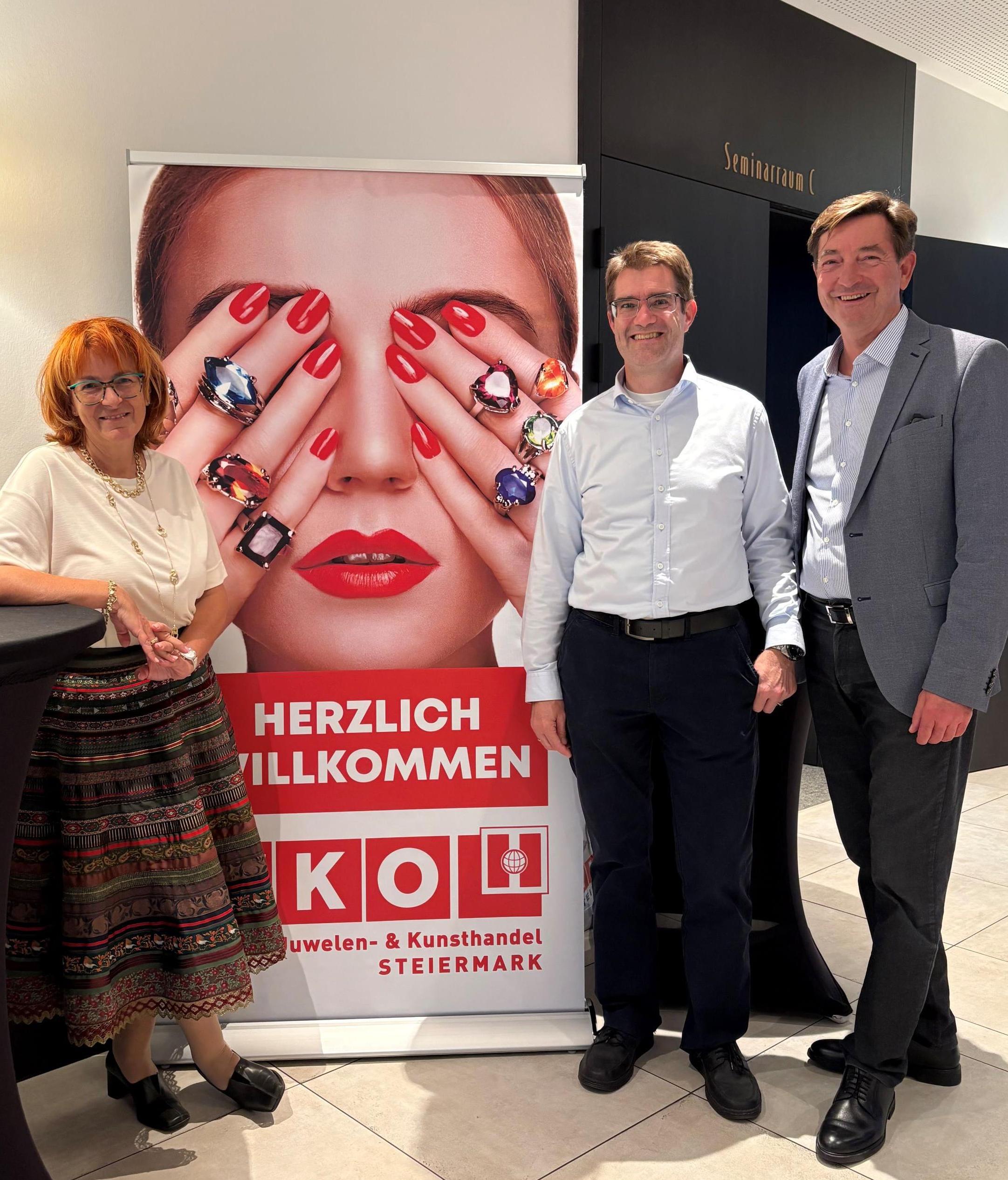 zwei Männer und eine Frau stehen vor einem Roll-Up