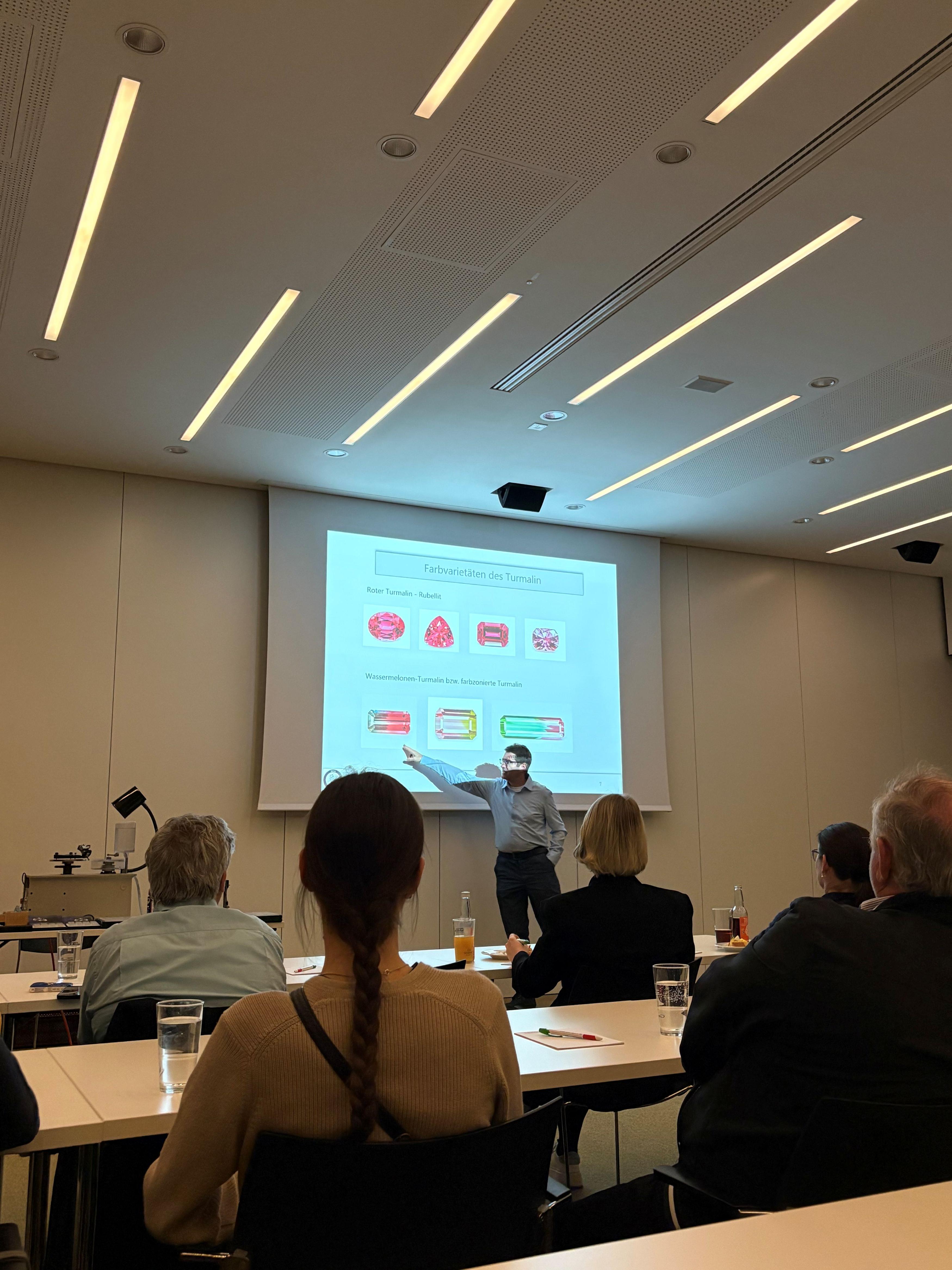 Seminarraum, Teilnehmer schauen dem Vortragenden zu der seinen Pr&auml;sentation h&auml;lt