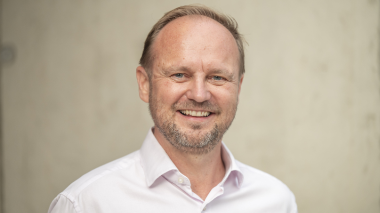 Porträt von einem Mann mit weißem Hemd vor einem verschwommenen Hintergrund