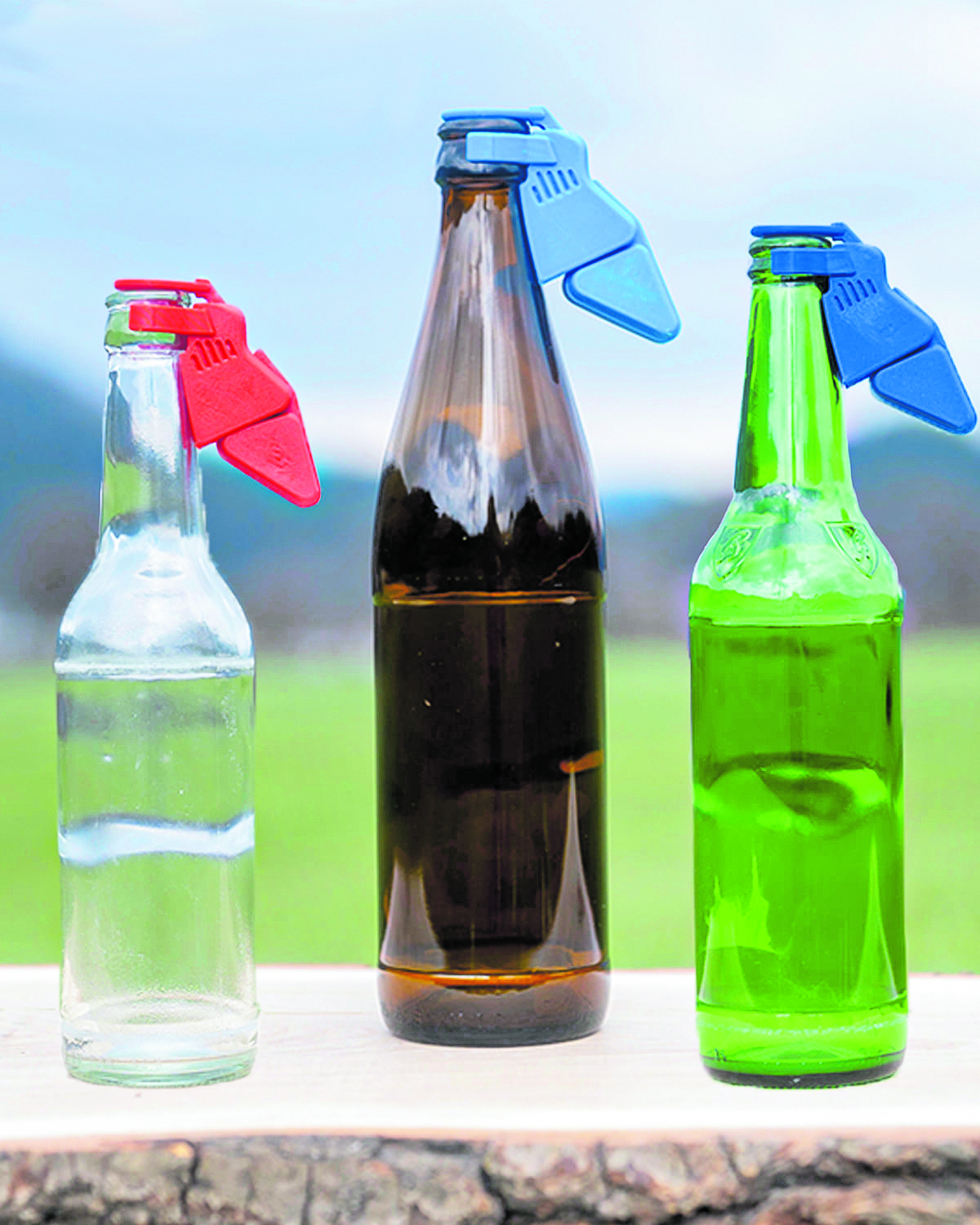 Drei Flaschen, unterschiedlich groß, mit verschiedenfärbigen Beerwilly-Aufsätzen