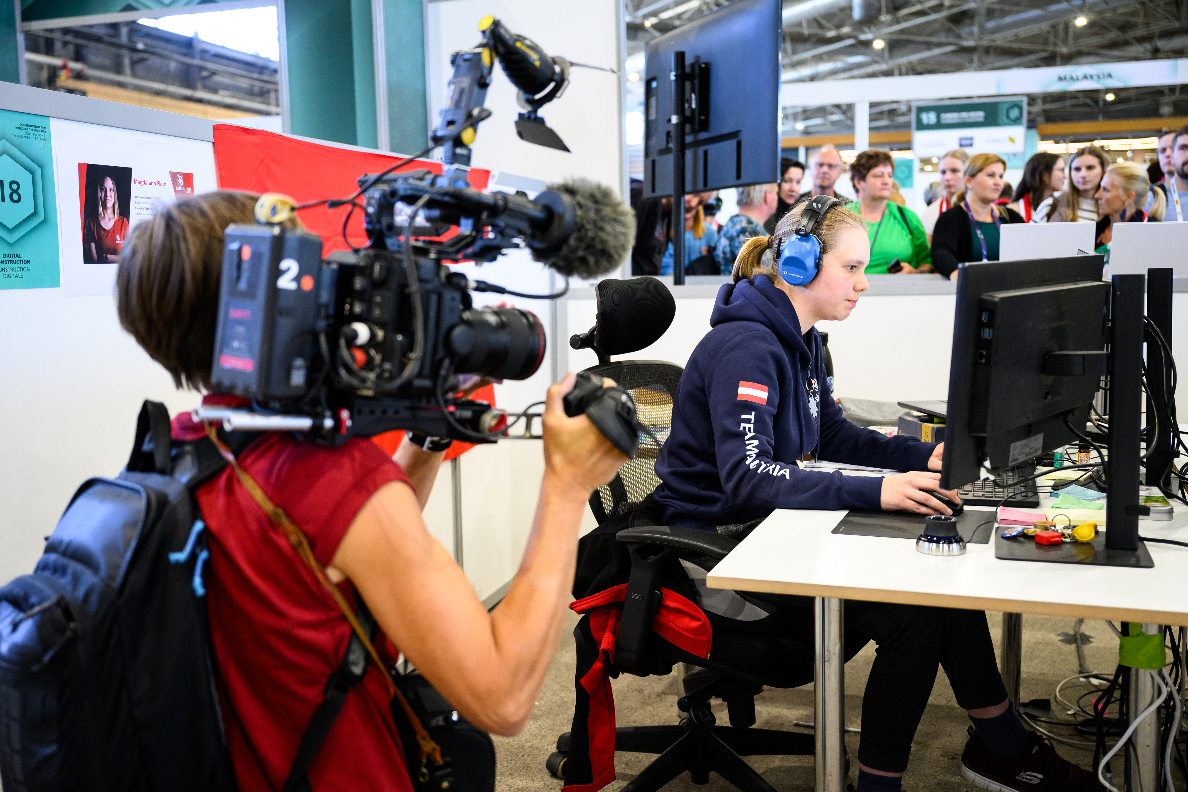 &Ouml;sterreichische Teilnehmerin bei den World Skills 2024 arbeitet konzentriert am PC und wird dabei von einem Kameramann gefilmt
