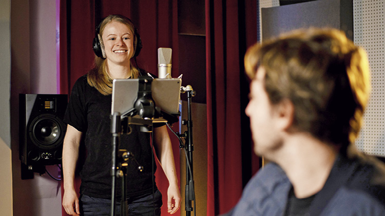 Eli Frauscher vor einem Mikro, sie l&auml;chelt in Richtung Horst Schnattler