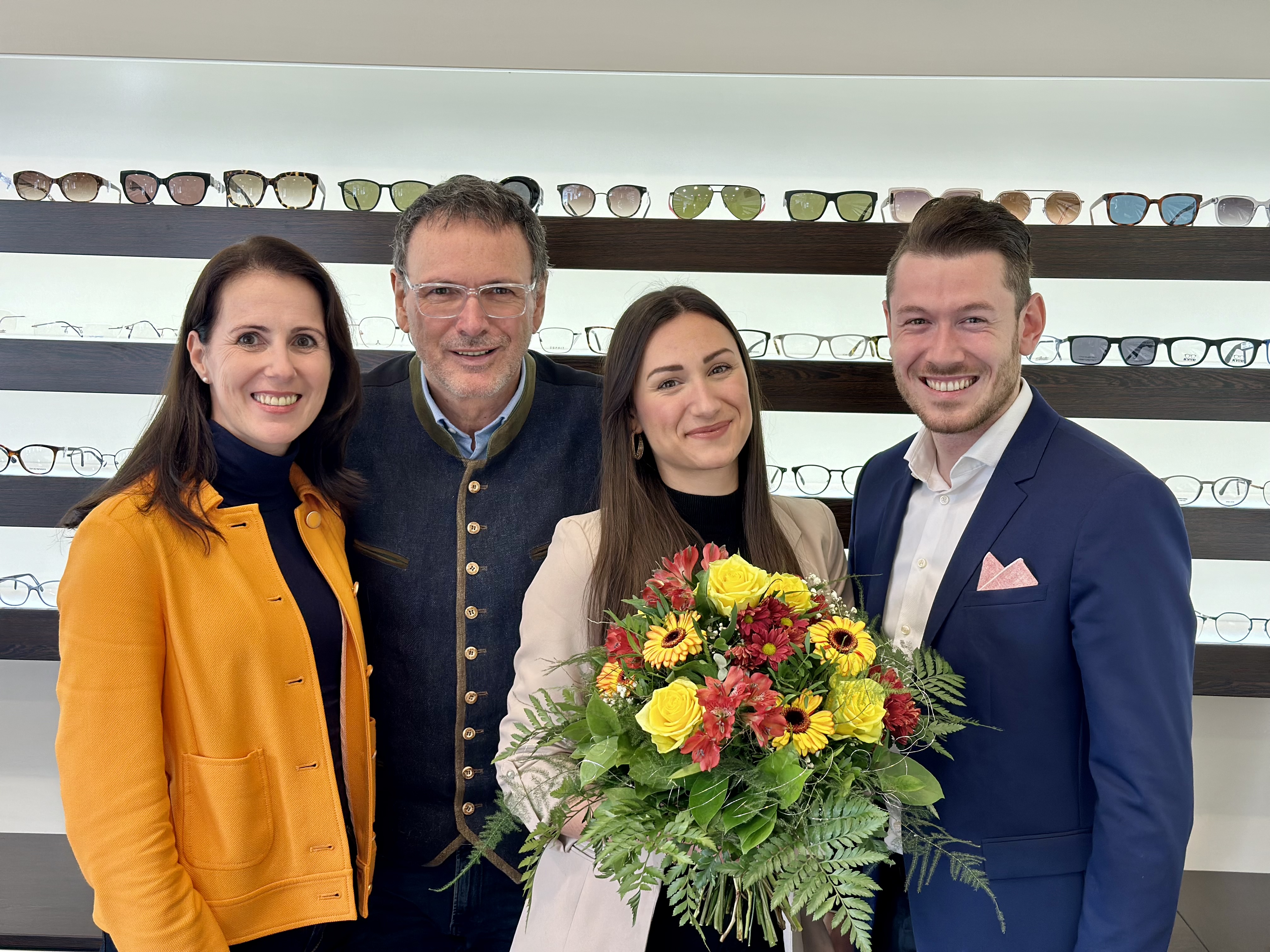 Anita Janek, Ekkhard, Claudia mit Blumenstrauß und Christopher Neuser (v.l.) vor einer Brillen-Wand
