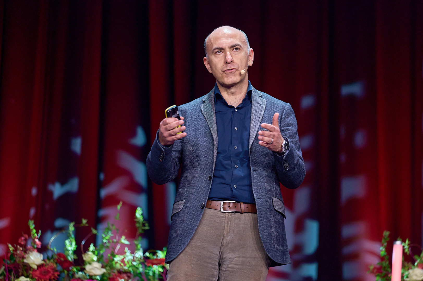 Nahuafnahme einer Person, die in der rechten Hand eine Fernbedienung hat. Die Person gestikuliert mit den Händen