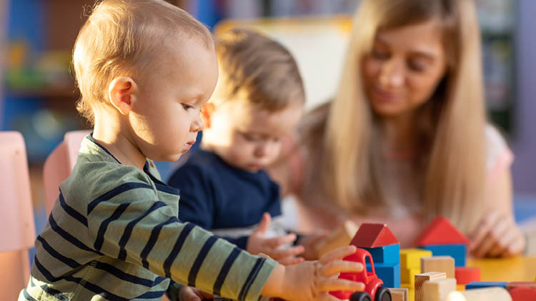 Kleinkind beim Spielen mit Plastikauto und Baukl&ouml;tzen