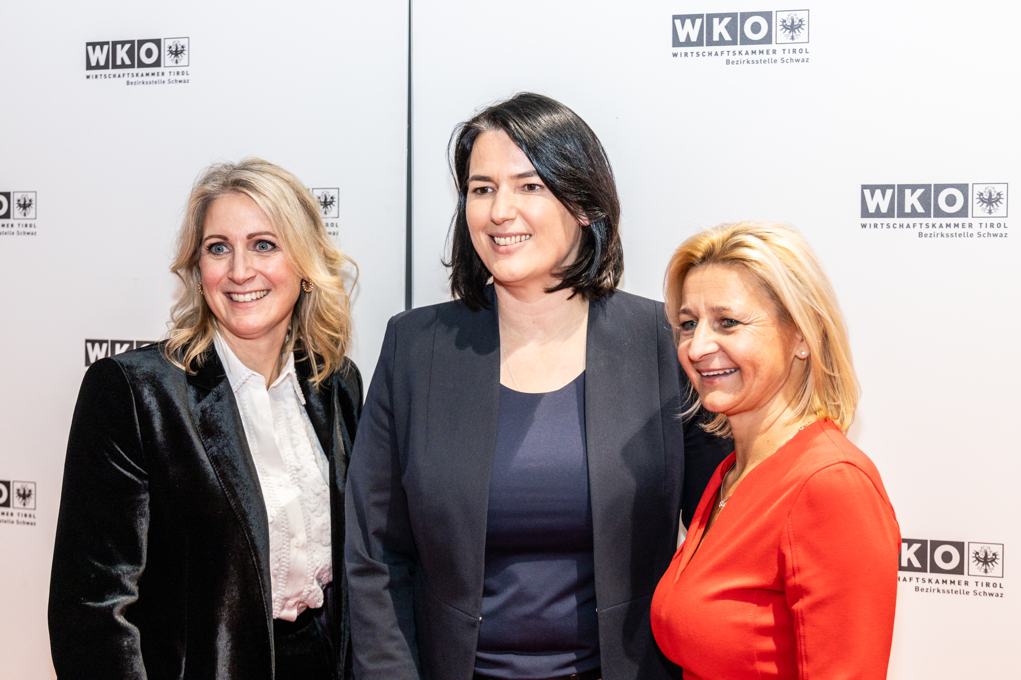 Drei Frauen stehen nebeneinander vor einer hellen Fotowand mit dem Logo der Wirtschaftskammer Tirol. Sie sind elegant gekleidet und l&auml;cheln in die Kamera. Die Frau in der Mitte tr&auml;gt ein dunkles Sakko, die beiden Frauen links und rechts helle bzw. farbige Kleidung. Es handelt sich um eine offizielle Veranstaltung in einem professionellen Umfeld.