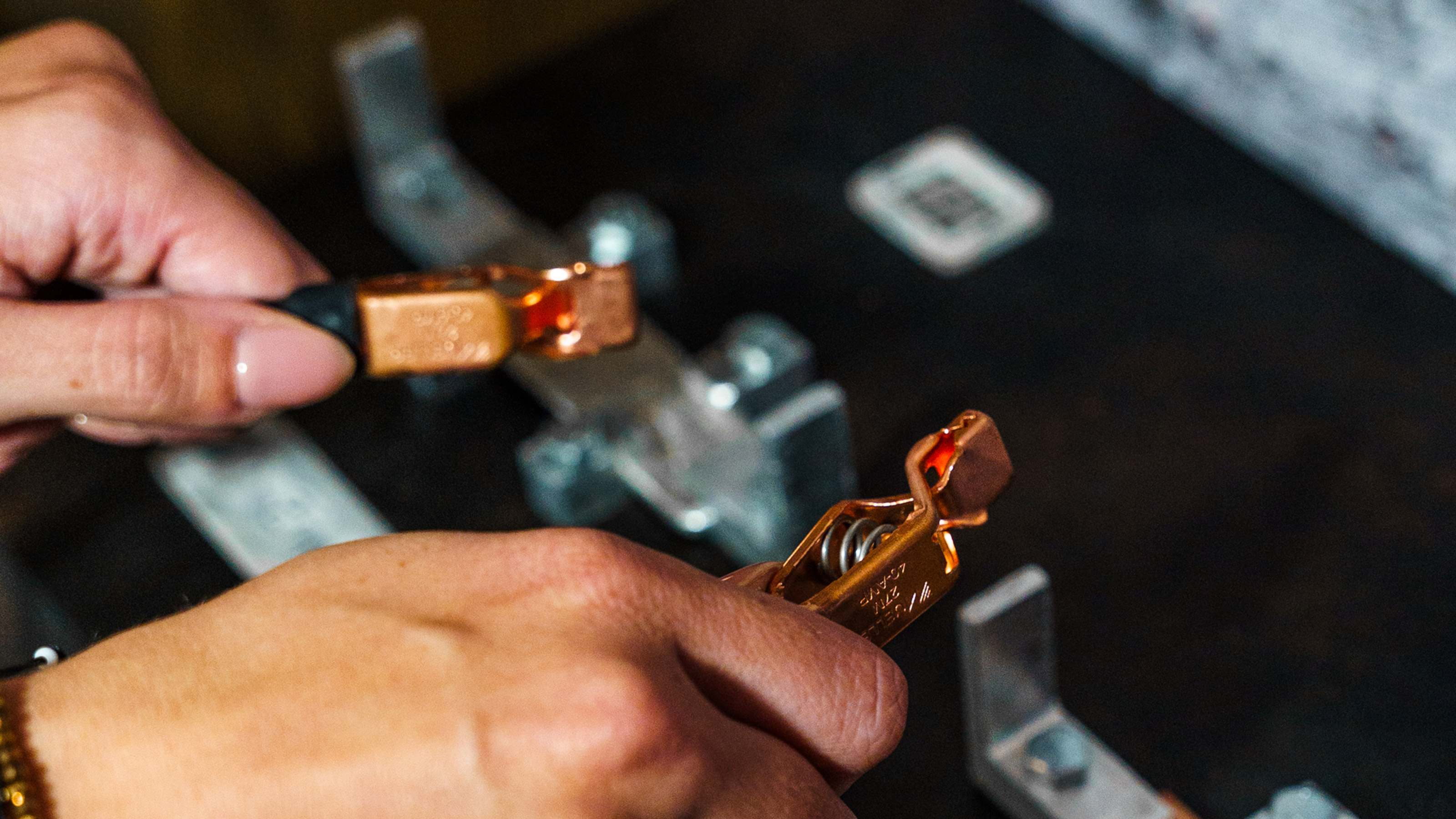 Zwei H&auml;nde im Vordergrund, die zwei Klemmen in der Hand halten