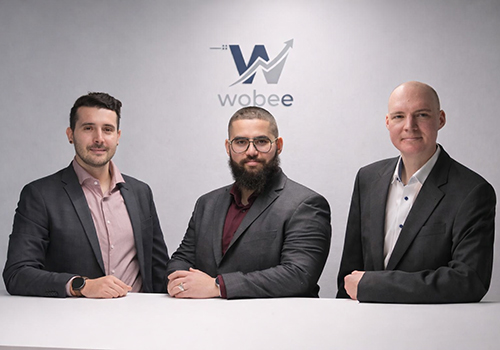 Foto mit 3 Personen und Logo im Hintergrund auf der Wand