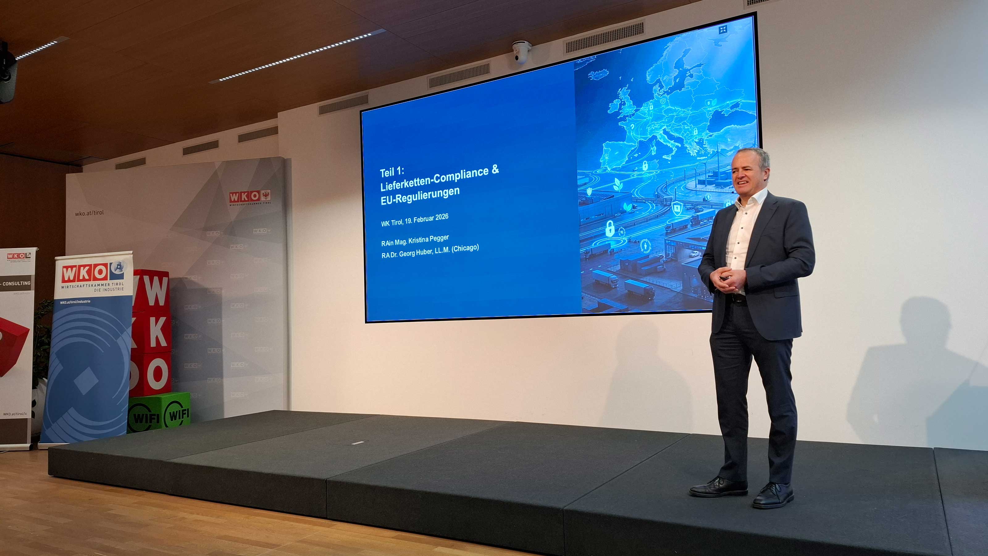 Veranstaltungssaal mit Publikum, am Podium steht ein Redner