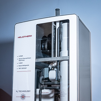 Stehendes Gerät einer Heliotherm-Hybrid-Wärmepumpe mit sichtbaren Leitungen und Komponenten hinter einer Glasfront.