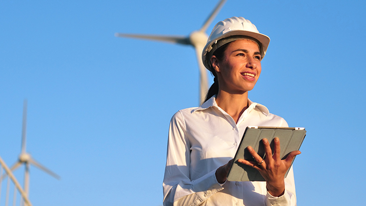 Ingeneurin mit Helm Tablet haltend in Ferne blickend im Hintergrund Windr&auml;der