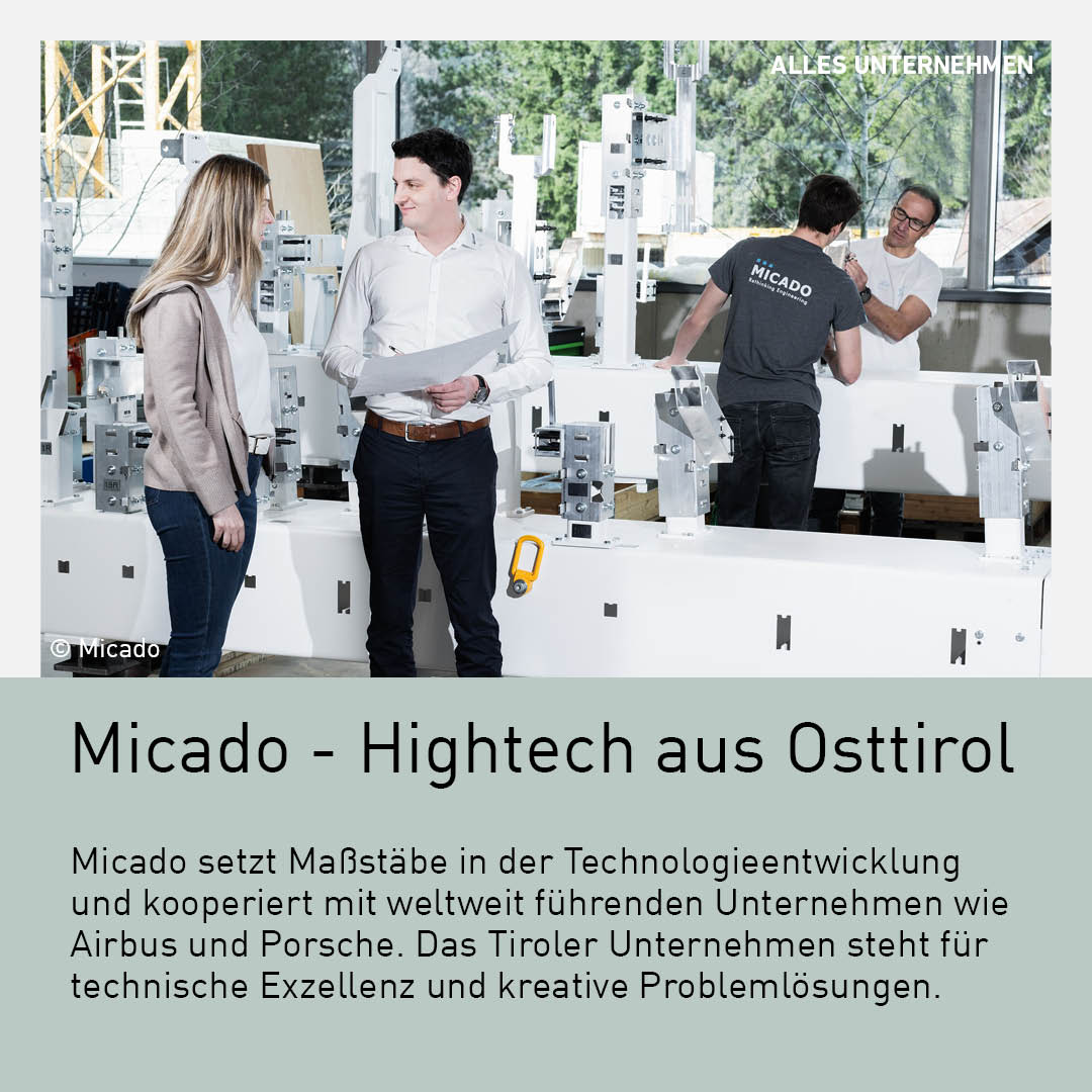 Micado Ingenieursteam arbeitet an Hightech-Maschinen in einer Fabrik in Osttirol. Zwei Ingenieure diskutieren über Baupläne, während ein weiterer Techniker im Hintergrund an einer Vorrichtung arbeitet