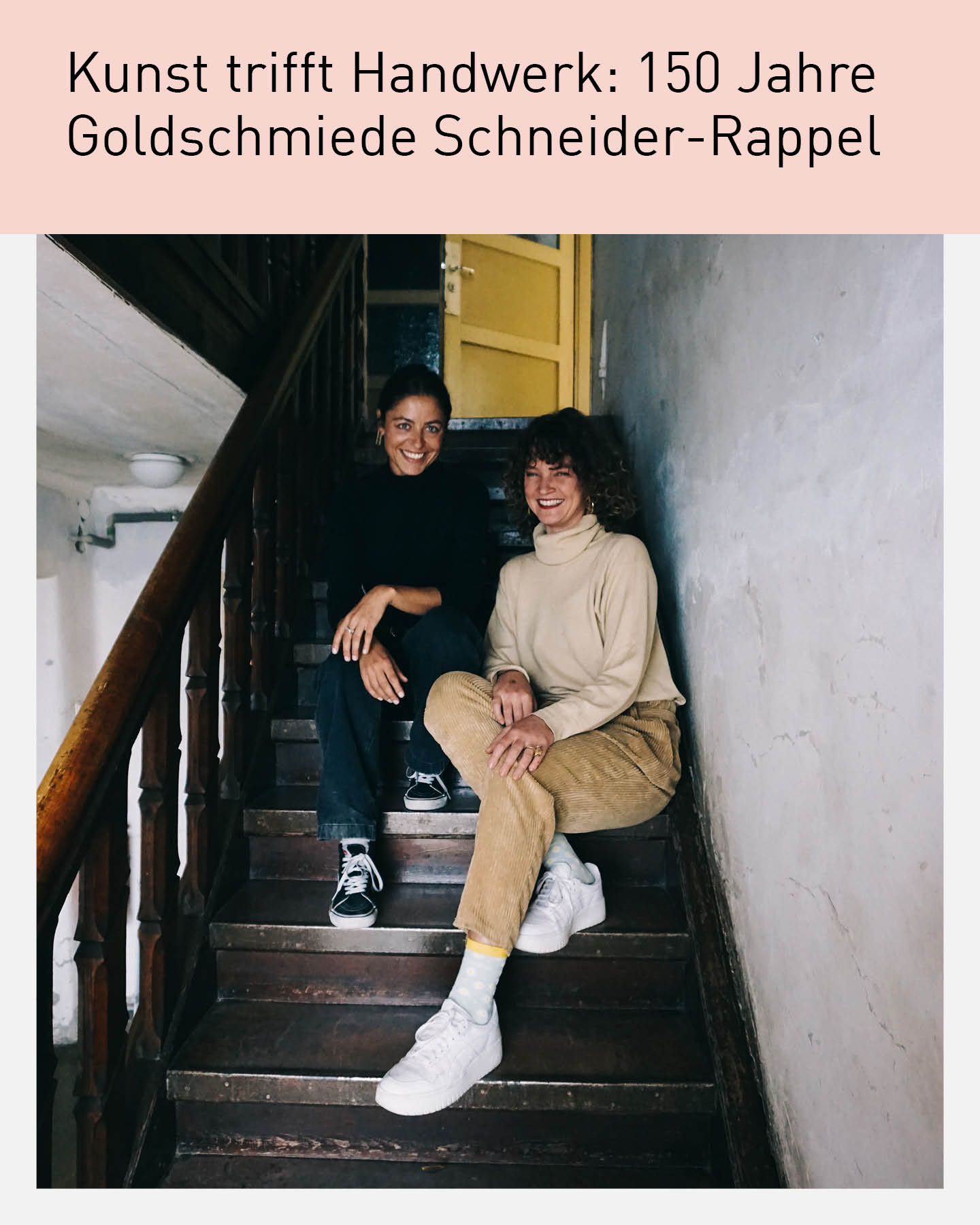 Zwei Personen sitzen auf einer alten Holztreppe in einem historischen Gebäude. Beide lächeln in die Kamera. Über dem Foto steht der Text „Kunst trifft Handwerk: 150 Jahre Goldschmiede Schneider-Rappel“.