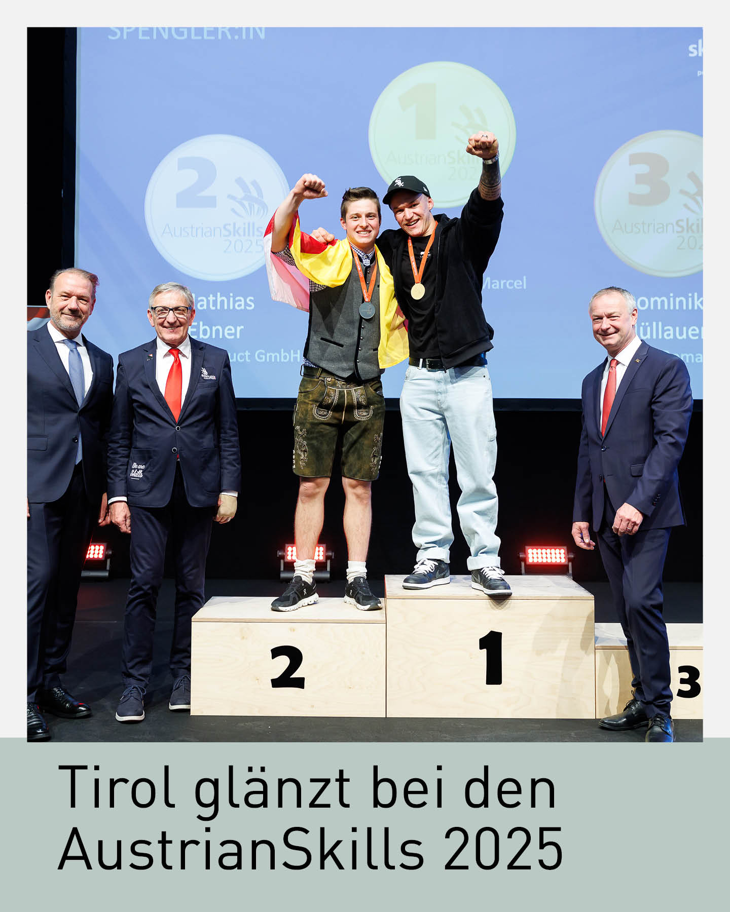 Podiumsaufnahme bei den AustrianSkills 2025: Zwei junge Fachkräfte stehen jubelnd auf den Plätzen eins und zwei, beide mit Medaillen um den Hals. Rechts und links daneben stehen drei Offizielle in Anzügen. Im Hintergrund sind die Siegerlogos der Kategorien eingeblendet. Festliche Bühnenatmosphäre mit klarer Ausleuchtung.