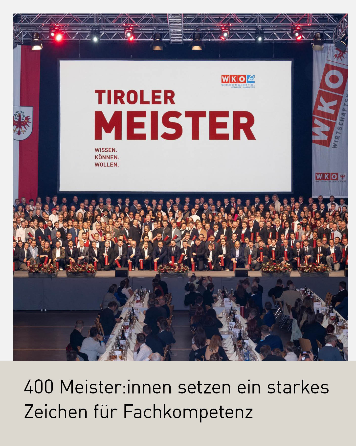 Große Meister:innen-Feier in der Wirtschaftskammer Tirol: Rund 400 Absolvent:innen sitzen und stehen auf der Bühne der Dogana im Congress Innsbruck, vor einer Leinwand mit der Aufschrift „Tiroler Meister“. Im Vordergrund sind festlich gedeckte Tische und zahlreiche Gäste zu sehen.