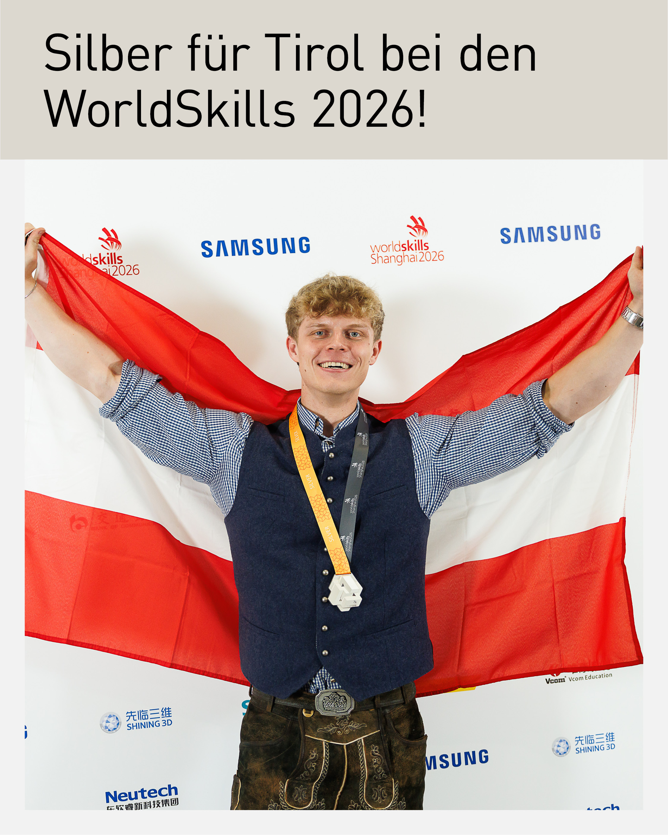 Vincent Track aus Breitenbach am Inn präsentiert seine Silbermedaille vor der österreichischen Fahne bei den WorldSkills 2026 in Shanghai. Der Tiroler wurde Vizeweltmeister in der Verfahrens- und Prozesstechnik.