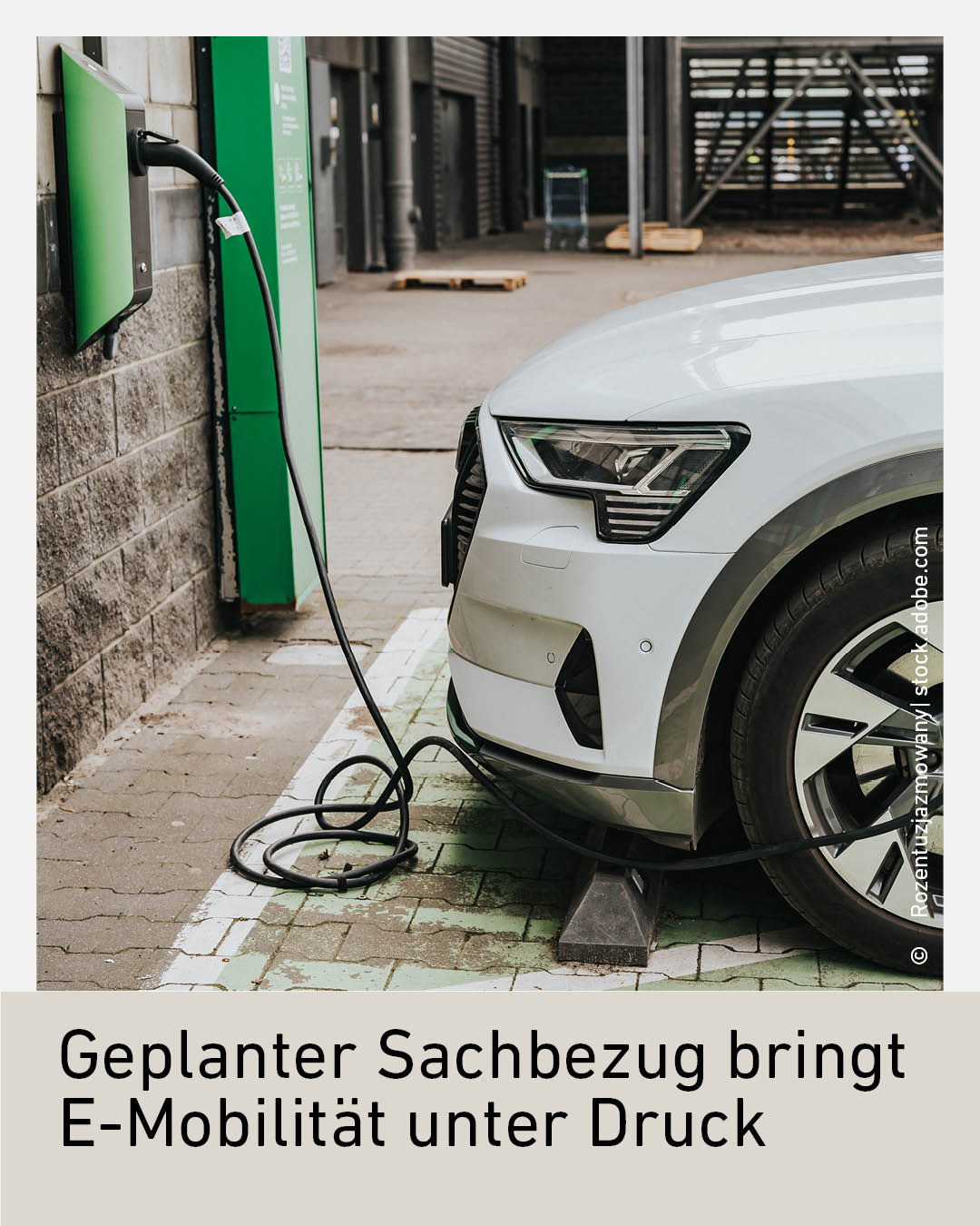 Ein wei&szlig;es Elektroauto an einer Ladestation an einem Geb&auml;ude.
