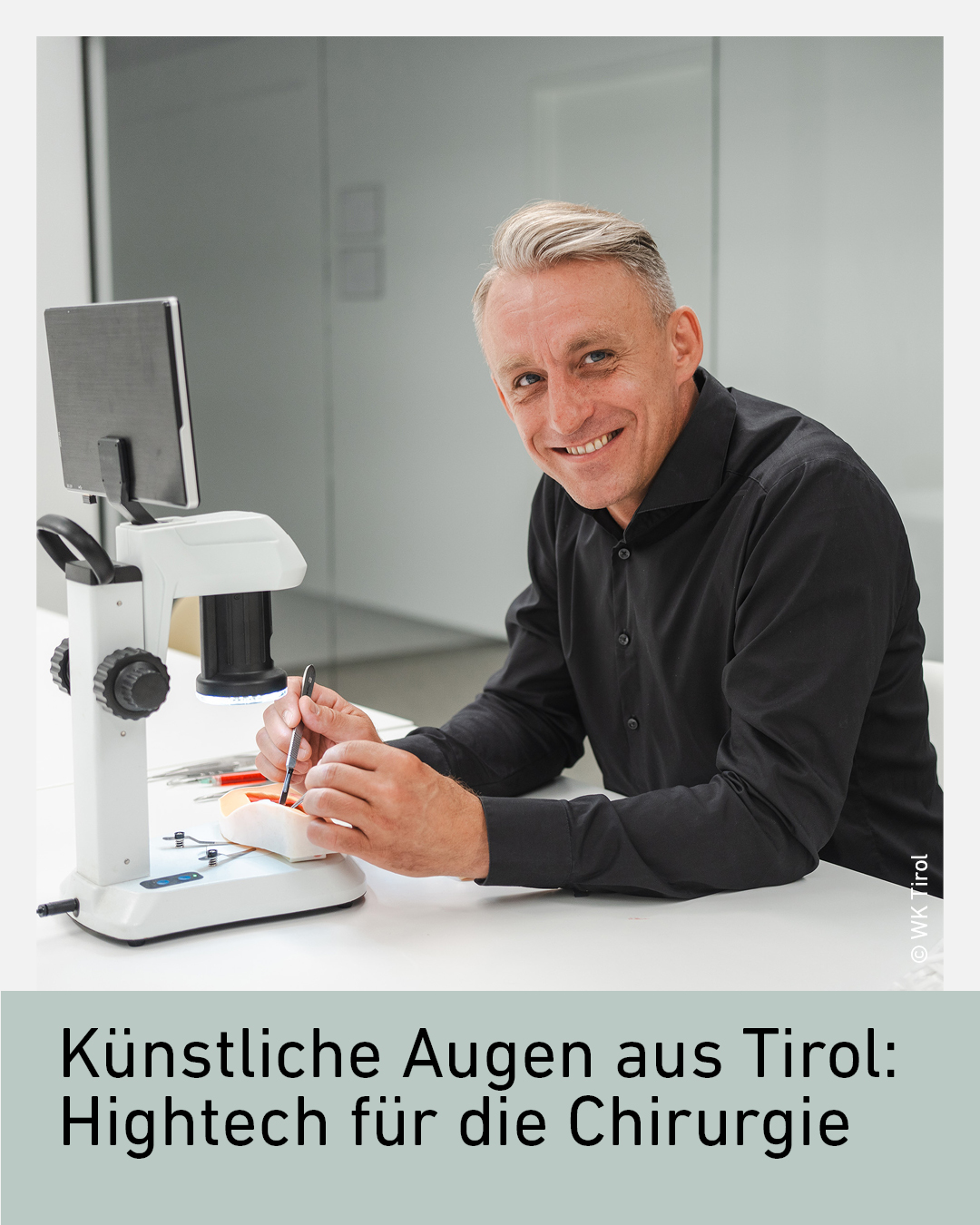 Ein lächelnder Mann in einem sterilen Raum vor einem Mikroskop.
