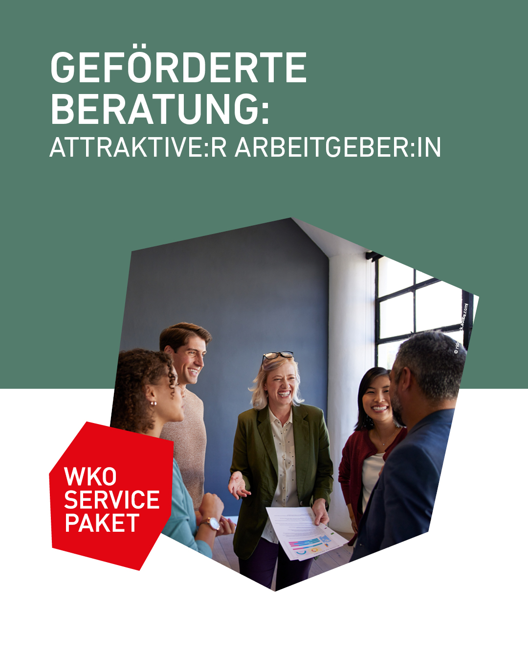 Eine Gruppe von mehreren l&auml;chelnden Personen, die sich in einem B&uuml;roraum unterhalten und Unterlagen besprechen.