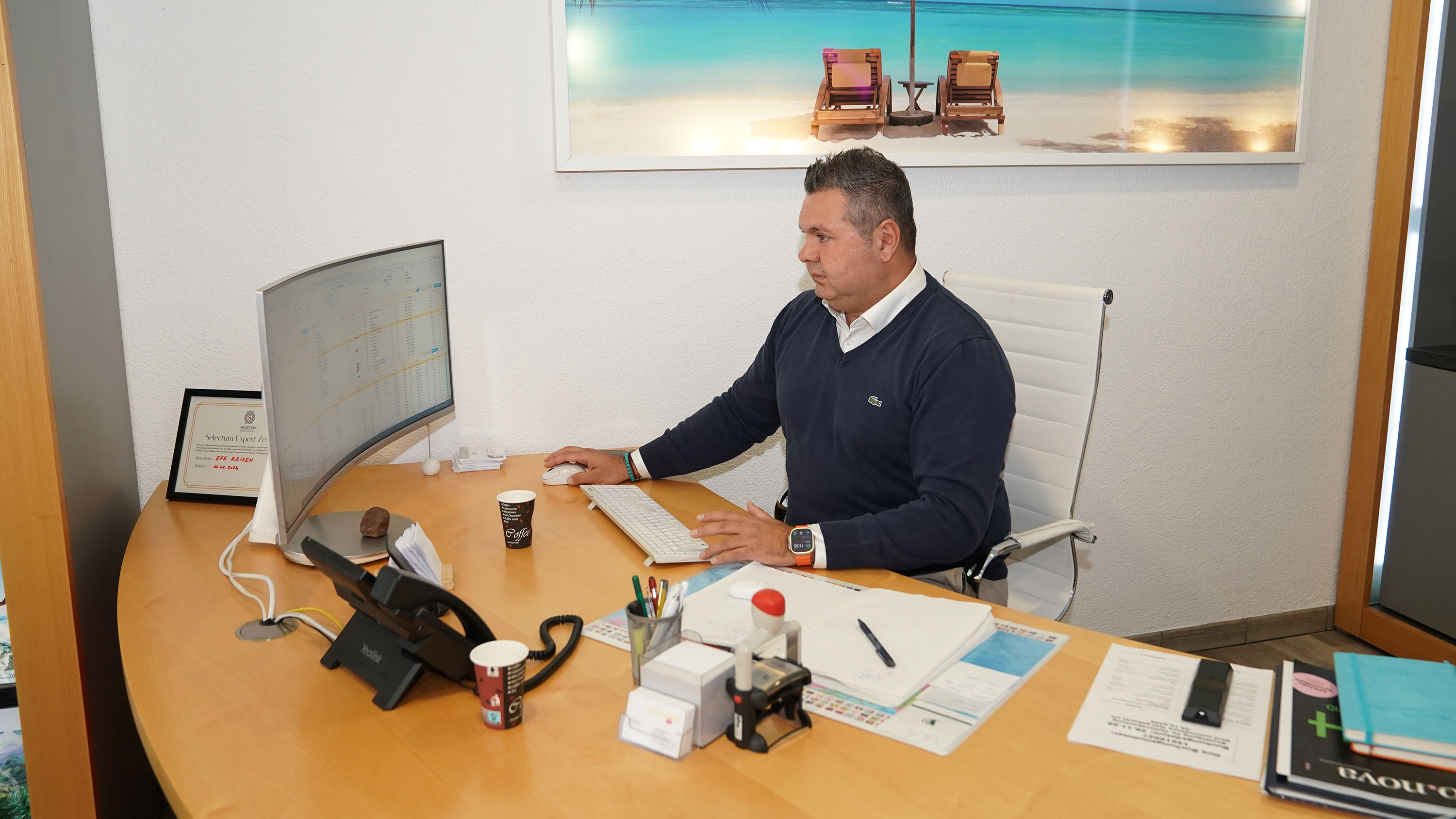 Bora Eker sitzt an seinem Schreibtisch und schaut in seinen Bildschirm hinein.