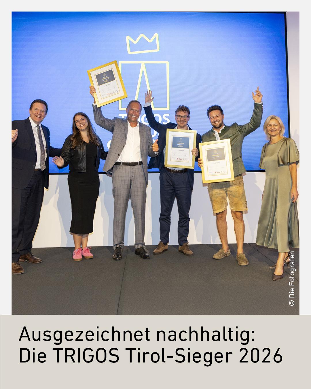 Sechs Personen stehen auf einer B&uuml;hne und halten Plaketten mit der Aufschrift &bdquo;Verbund&ldquo;, vor einem Hintergrund mit der TRIGOS-Logo und dem Wort &bdquo;TIROL&ldquo;.